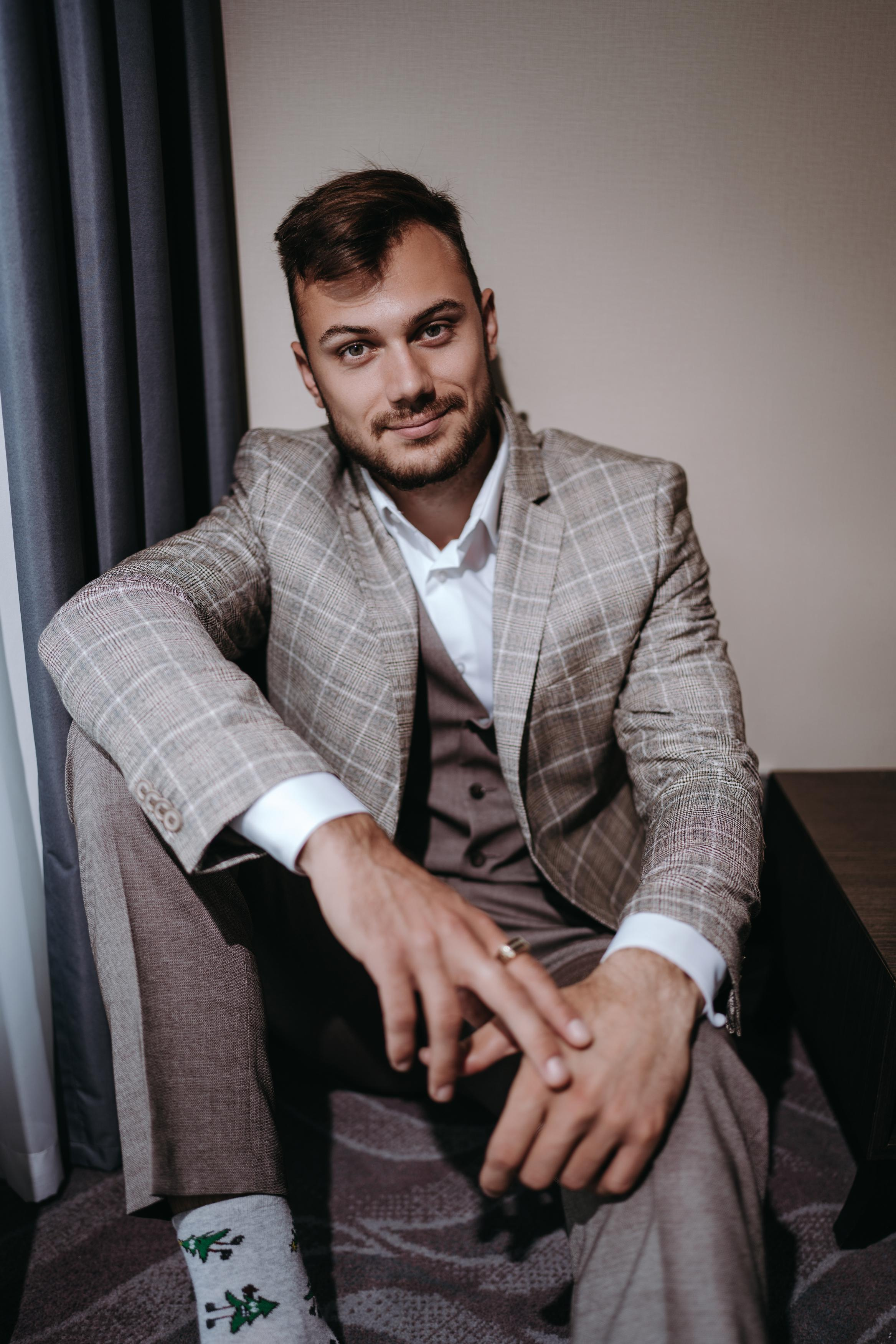 Портрет жениха который сидит на полу в номере отеля Шератон, стильные сборы жениха, идеи