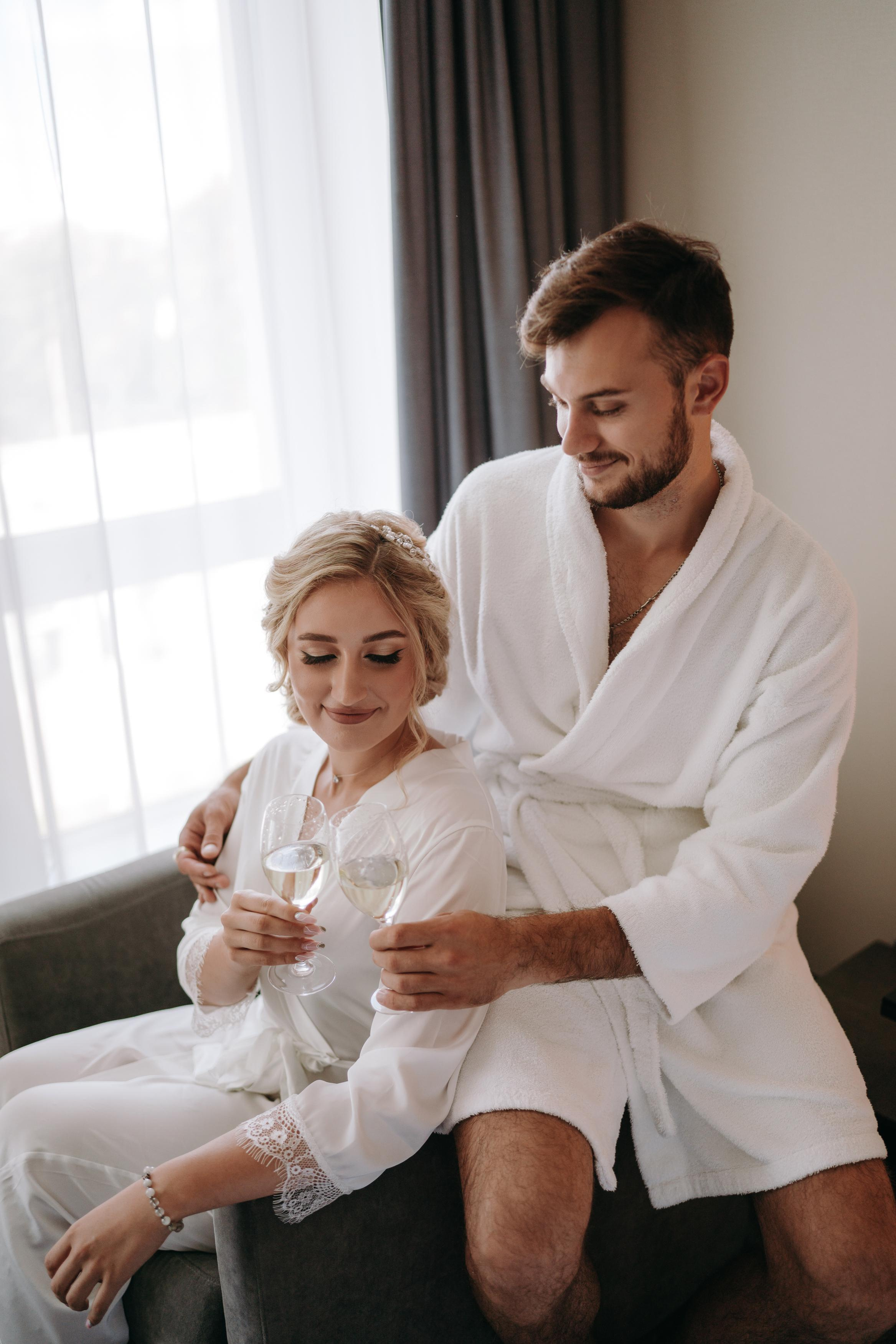 Невеста и жених пьют в номере шампанское, креативные сборы
