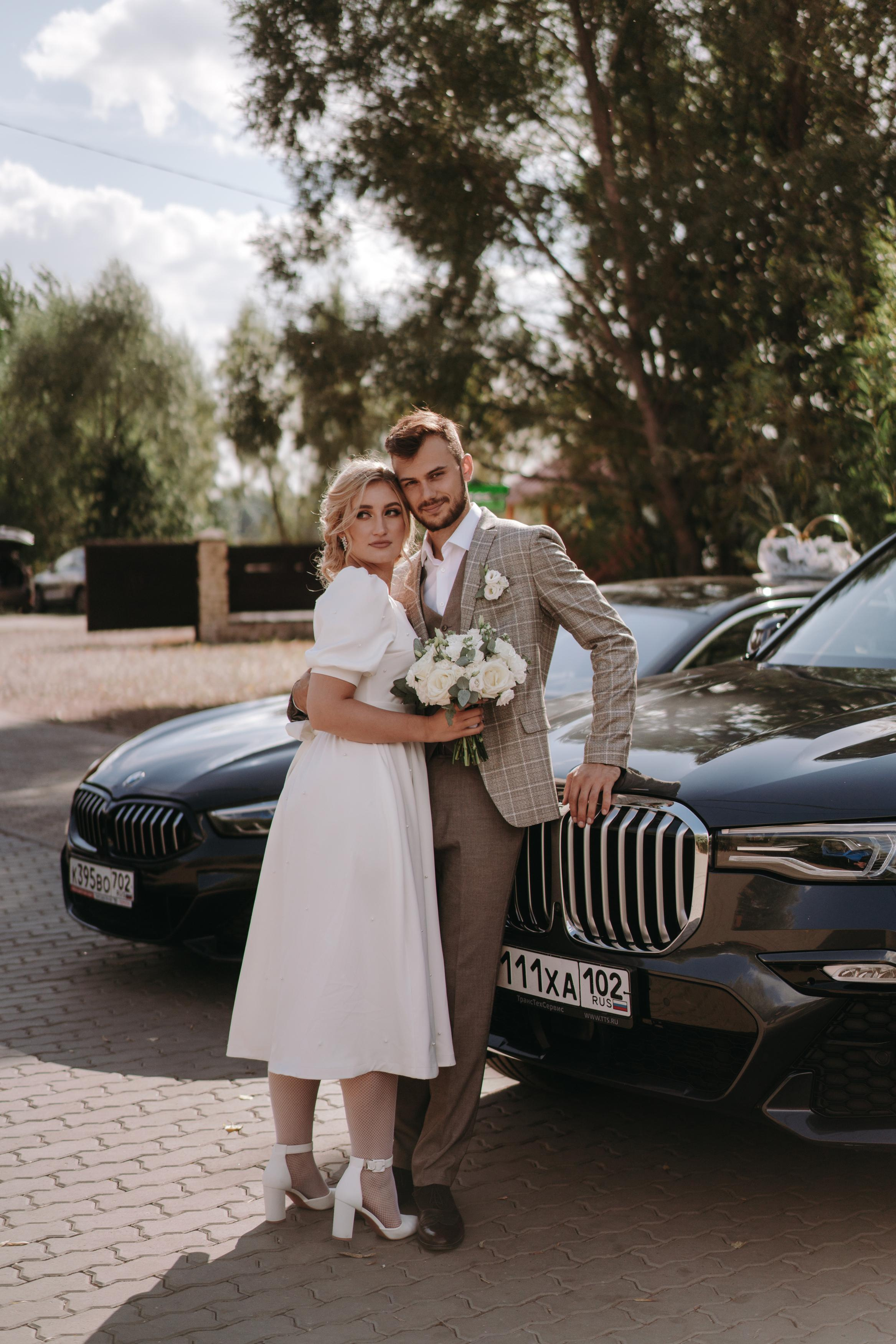 Жених и невста стоят на фоне бмв х7 в ильмурзино, в руках у невесты букет