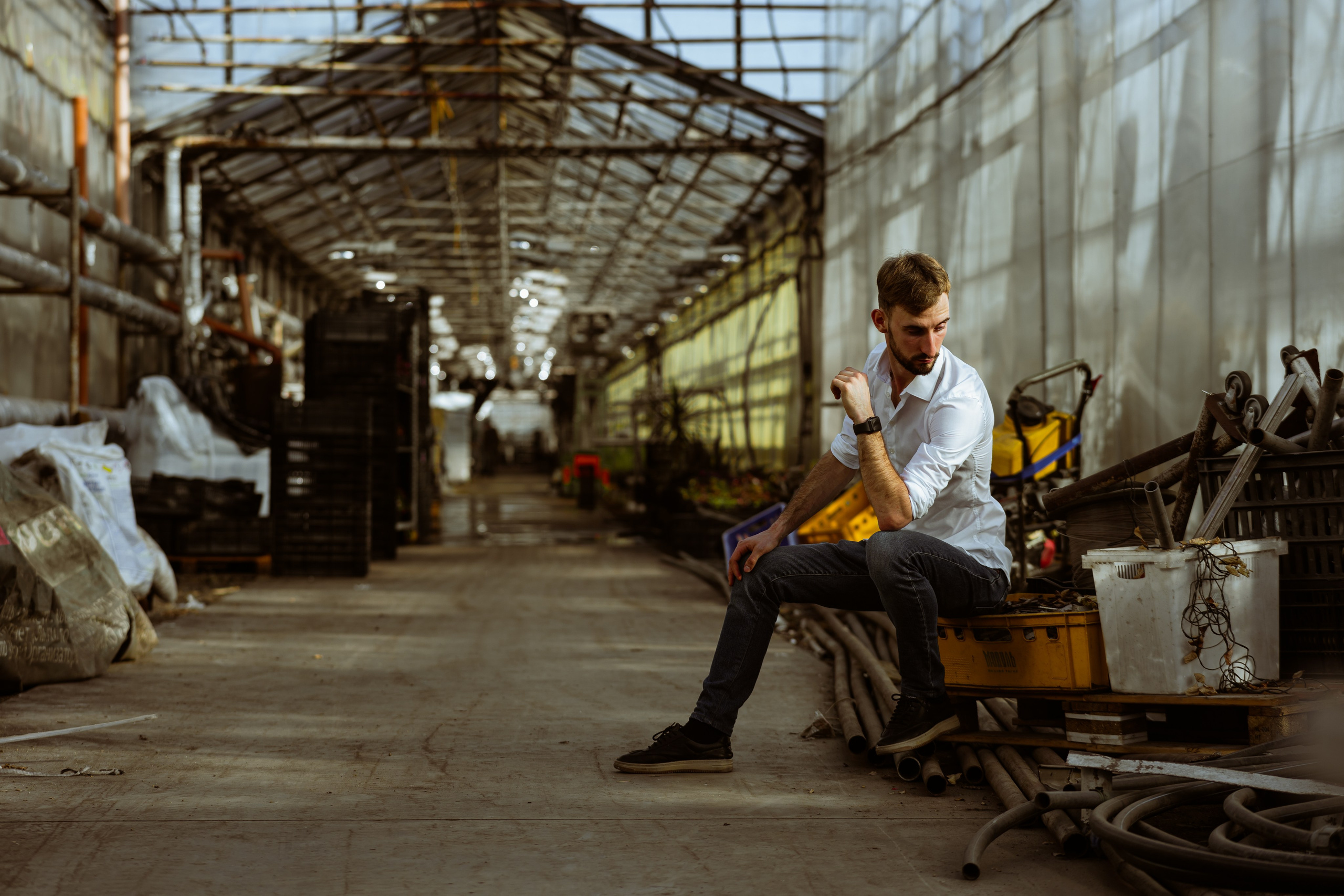 Мужчина в белой рубашке в заброшенной теплице, задумчивая поза, золотистый свет, Свердловская область, Илья Антропов