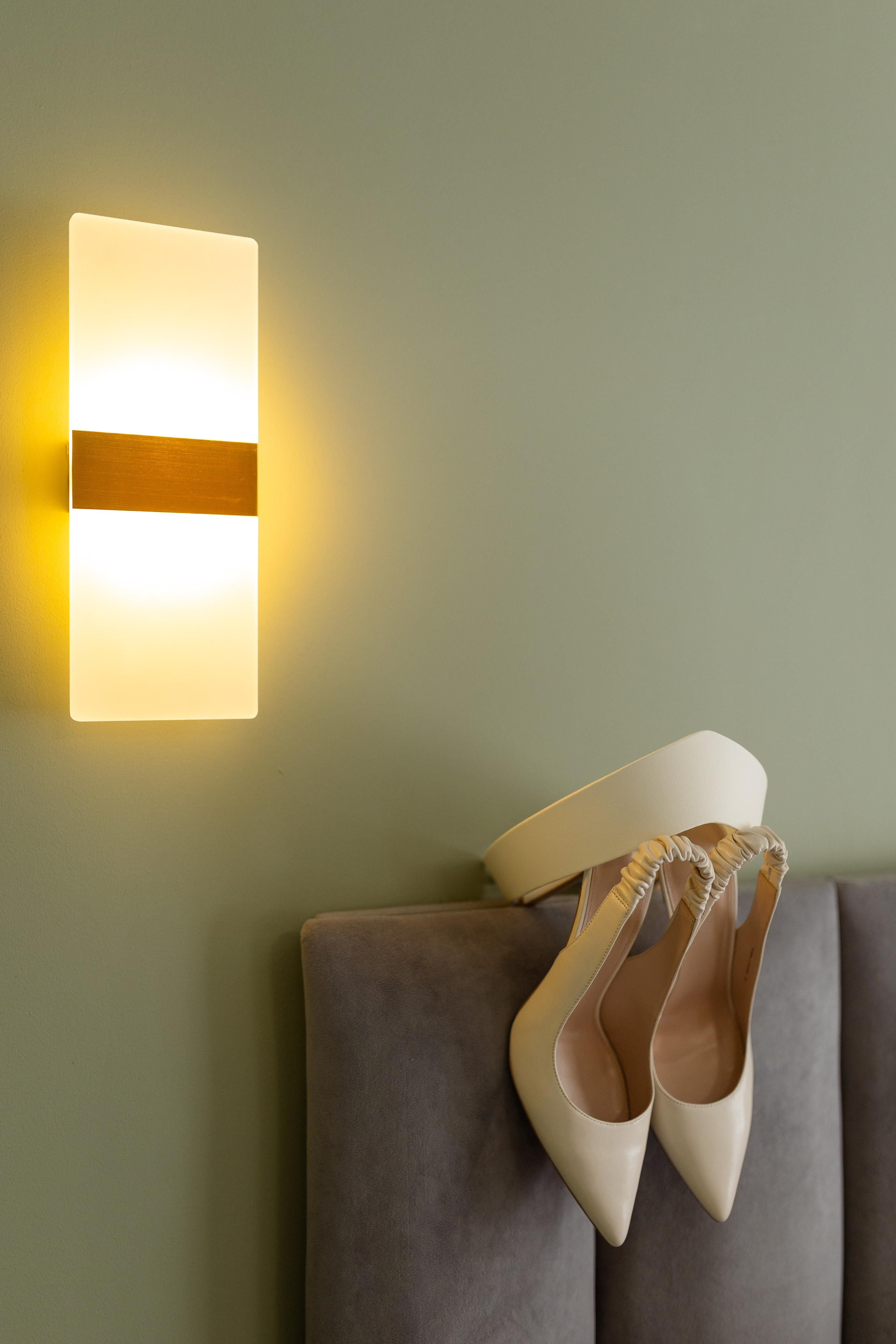 под светящимся на стене бра на подставке белые туфли.