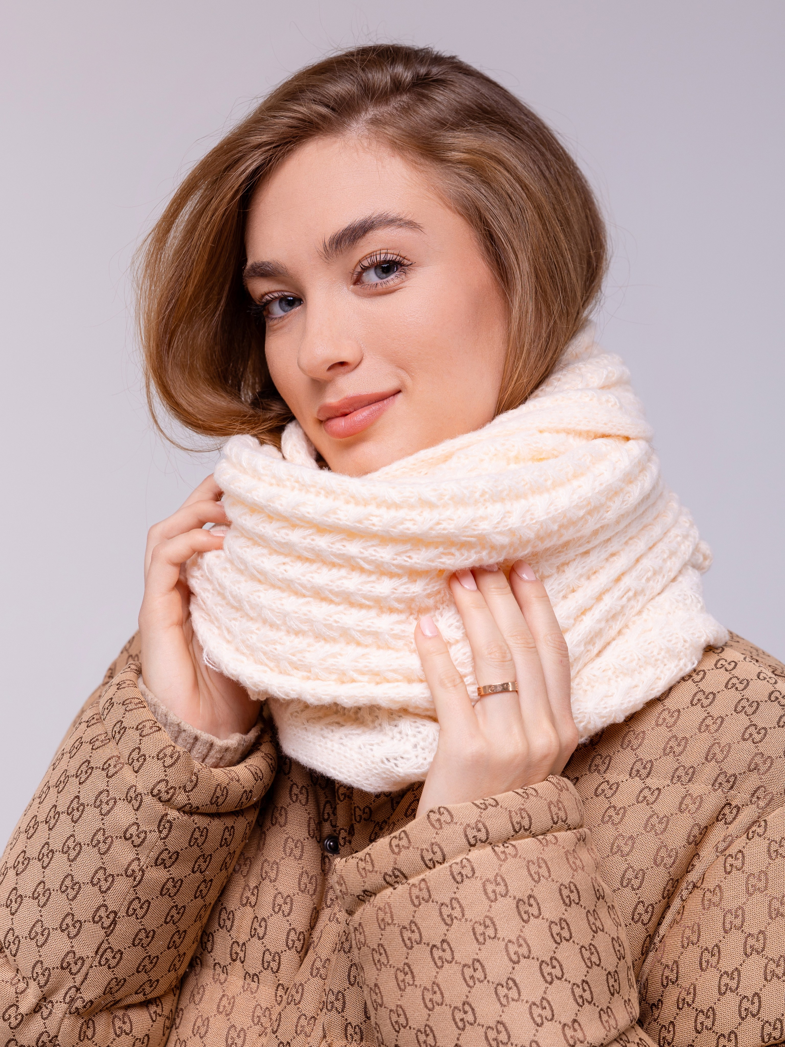 Белый шарф крупной вязки девушка обвязала вокруг шеи .