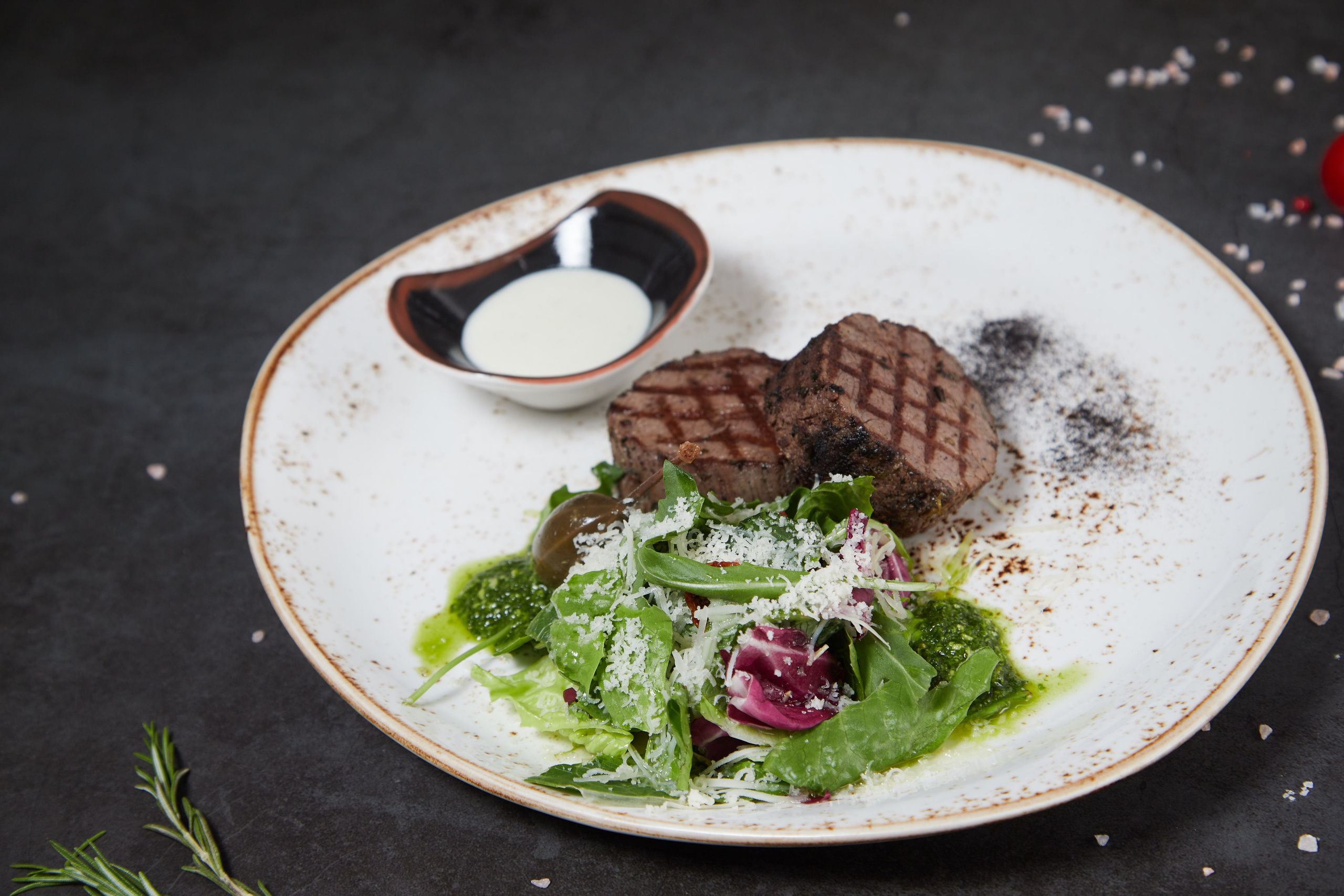 Стейк из говядины с соусом и овощным салатом.