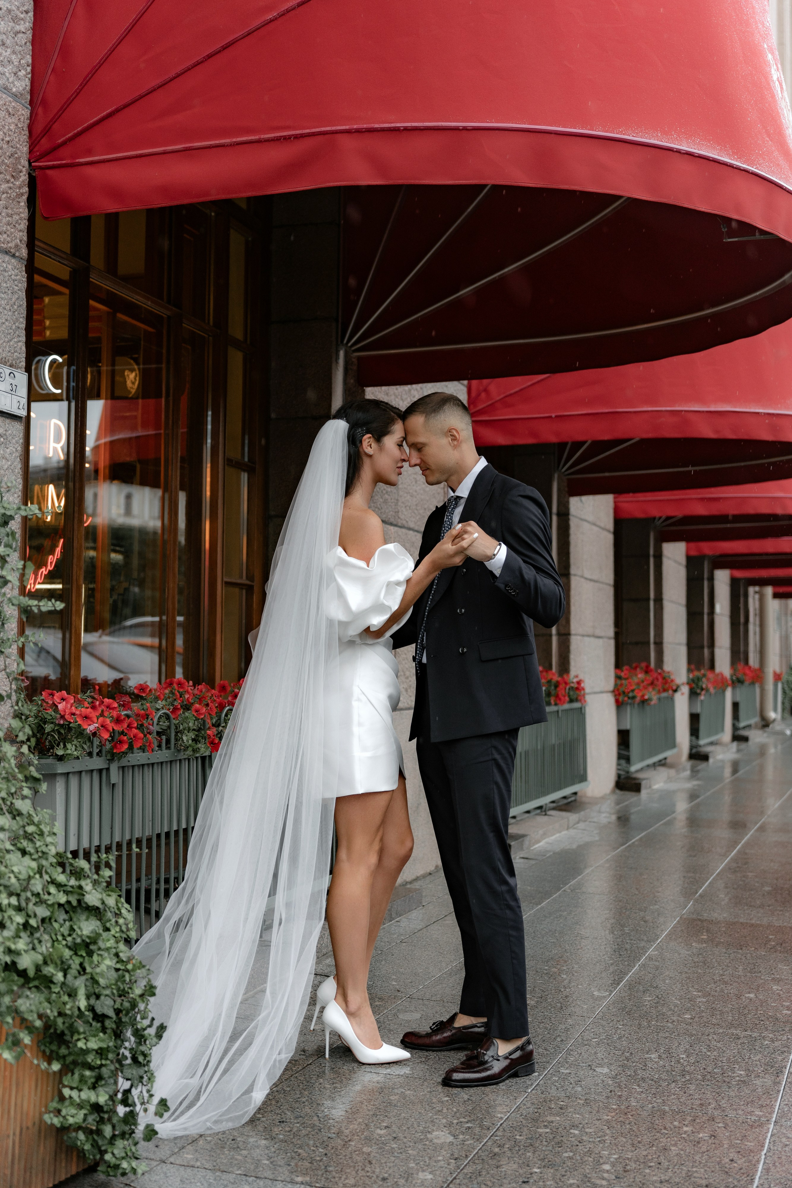 Свадебная фотосессия невесты и жениха у гостиницы Астория в Санкт-Петербурге под красными навесами