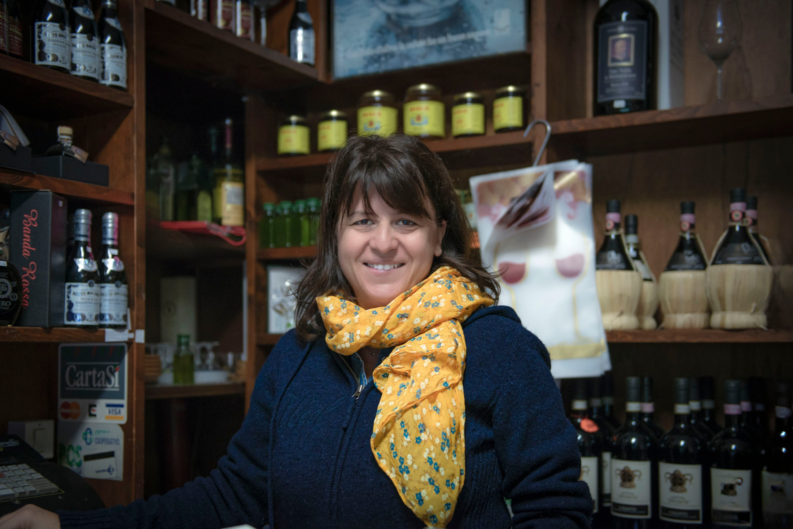 Портрет Морены Тистарелли, владелицы семейной маслобойни Frantoio Tistarelli, стоящей в их уютном магазине среди бутылок оливкового масла extra virgin