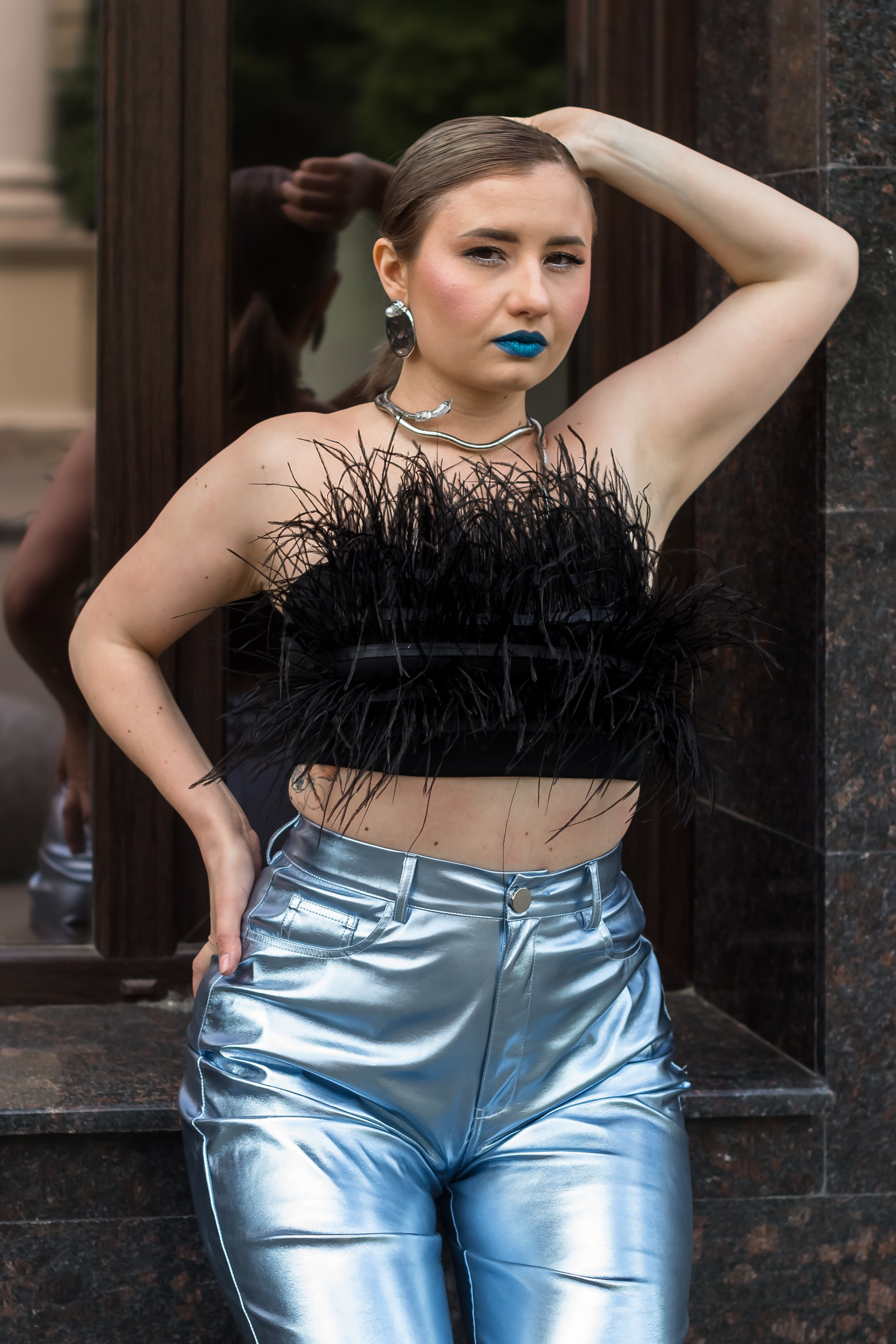 Портрет девушки в топике на улице, одна рука на бедре.