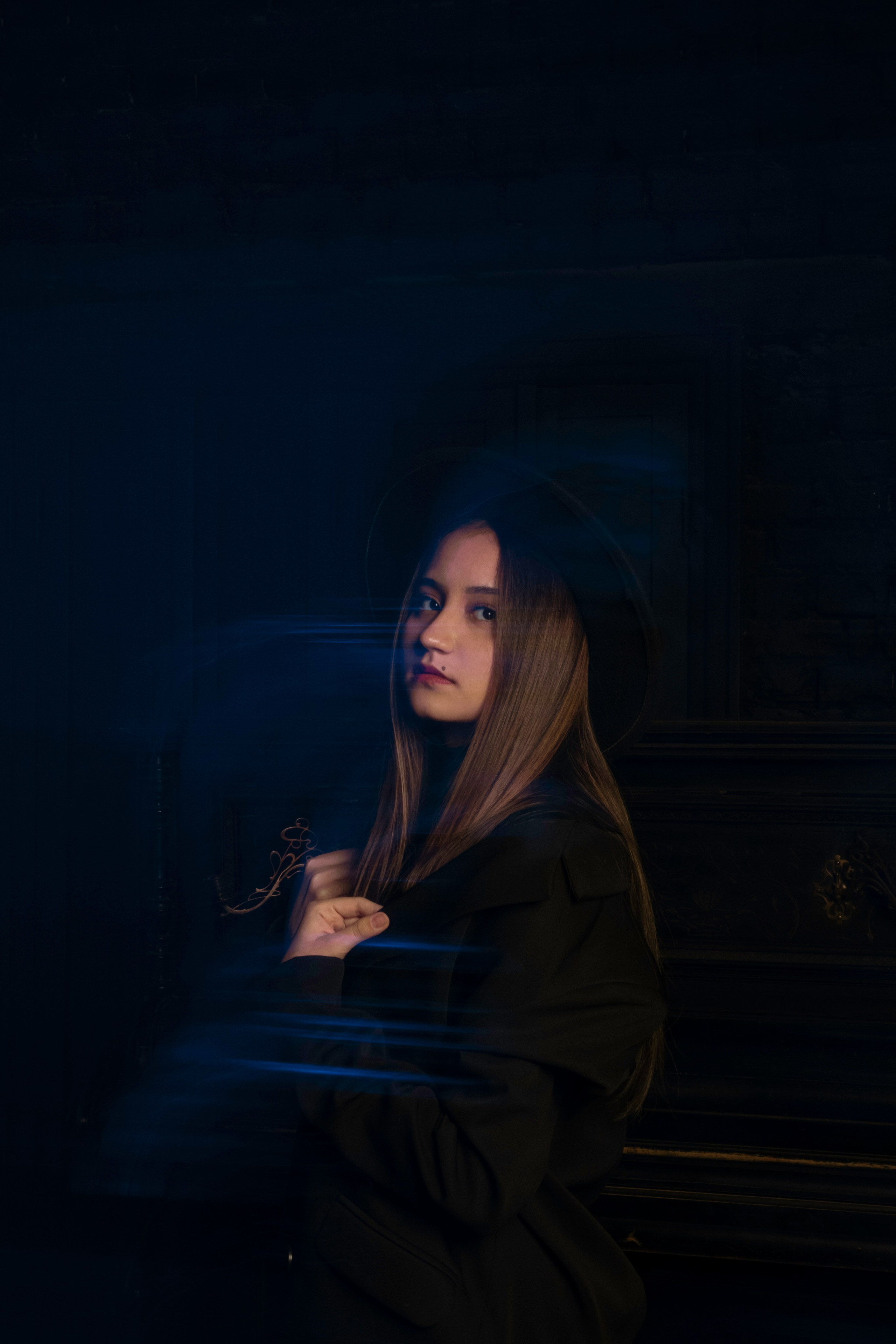 девушка фотографируется в шляпе со смешанным светом в синих тонах