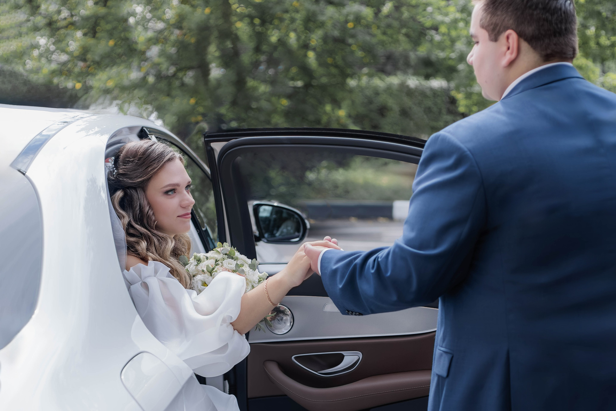 Свадебная фотосессия, жених помогает выйти невесте из машины