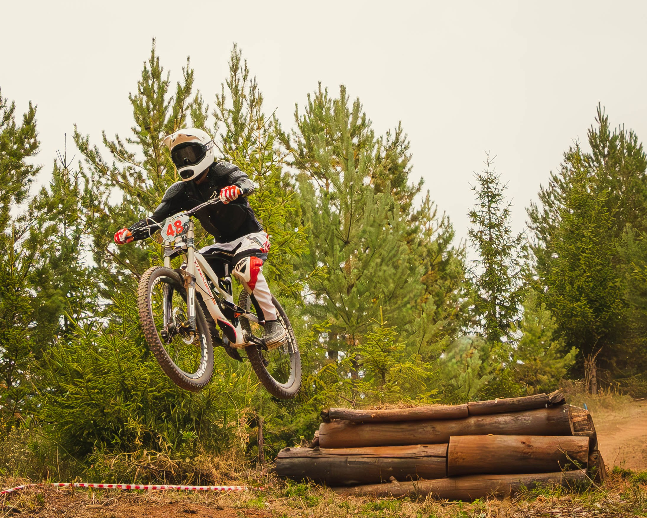 Велосипедист на соревнованиях по даунхилл прыгает через трамплин