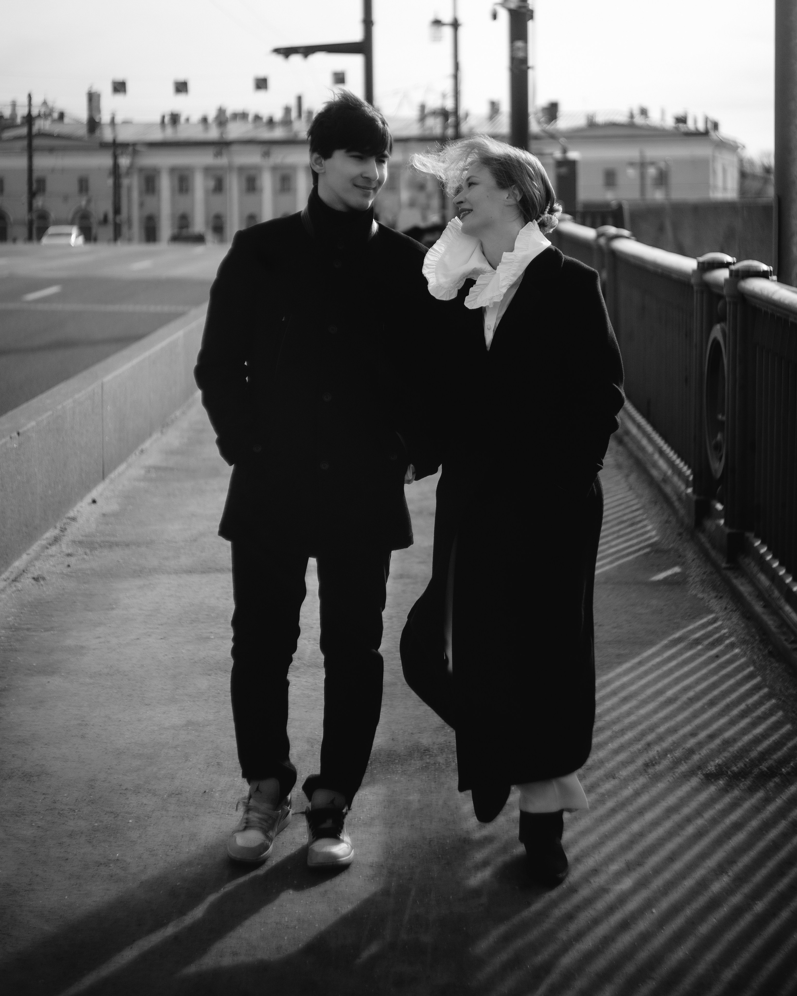 Черно-белая фотосессия пары на мосту, влюбленные идут рядом, авторская love story съемка в городской эстетике Санкт-Петербурга