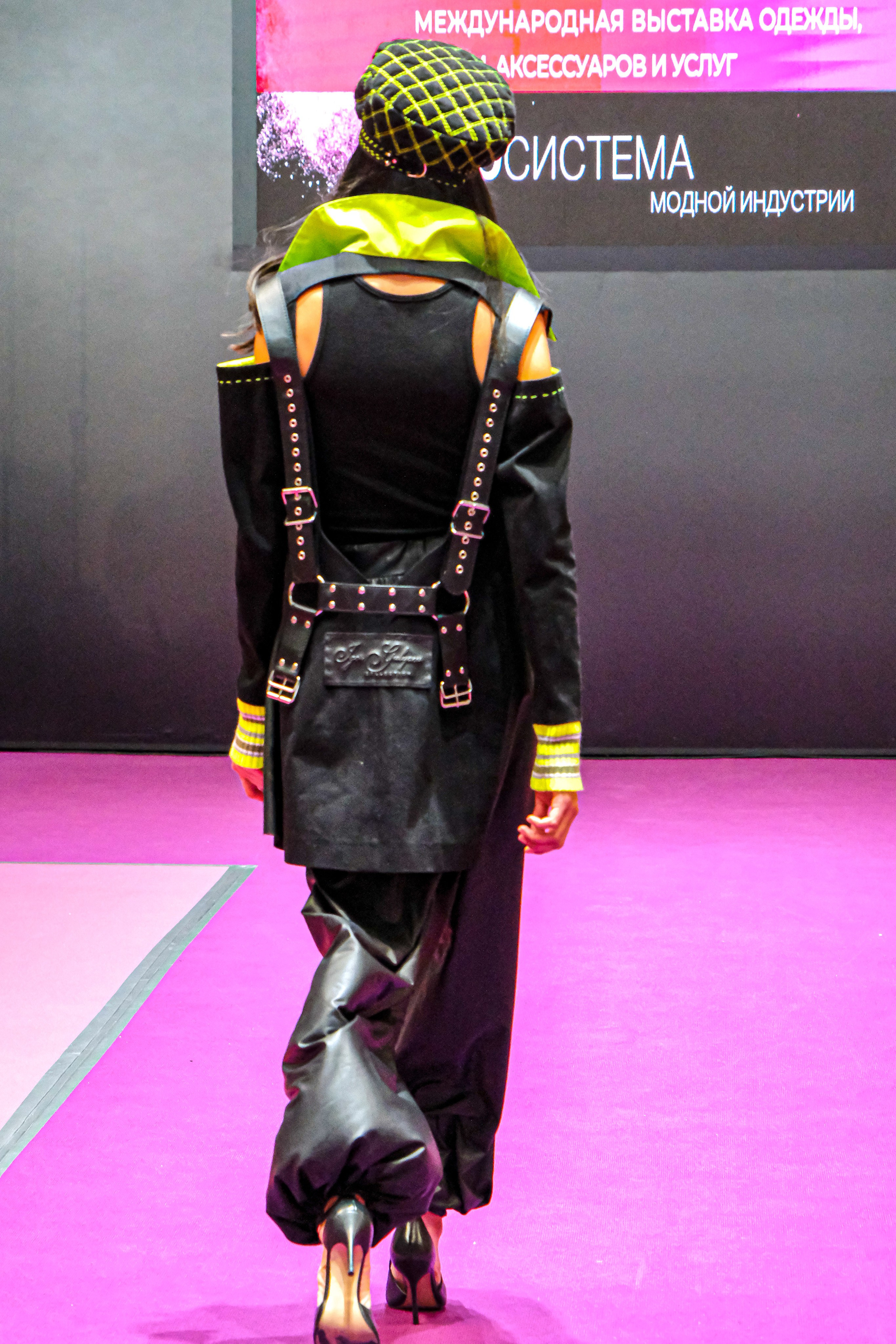  "Модели в ярких нарядах проходят по подиуму во время показа мод, освещенные яркими софитами и окруженные восторженными зрителями."