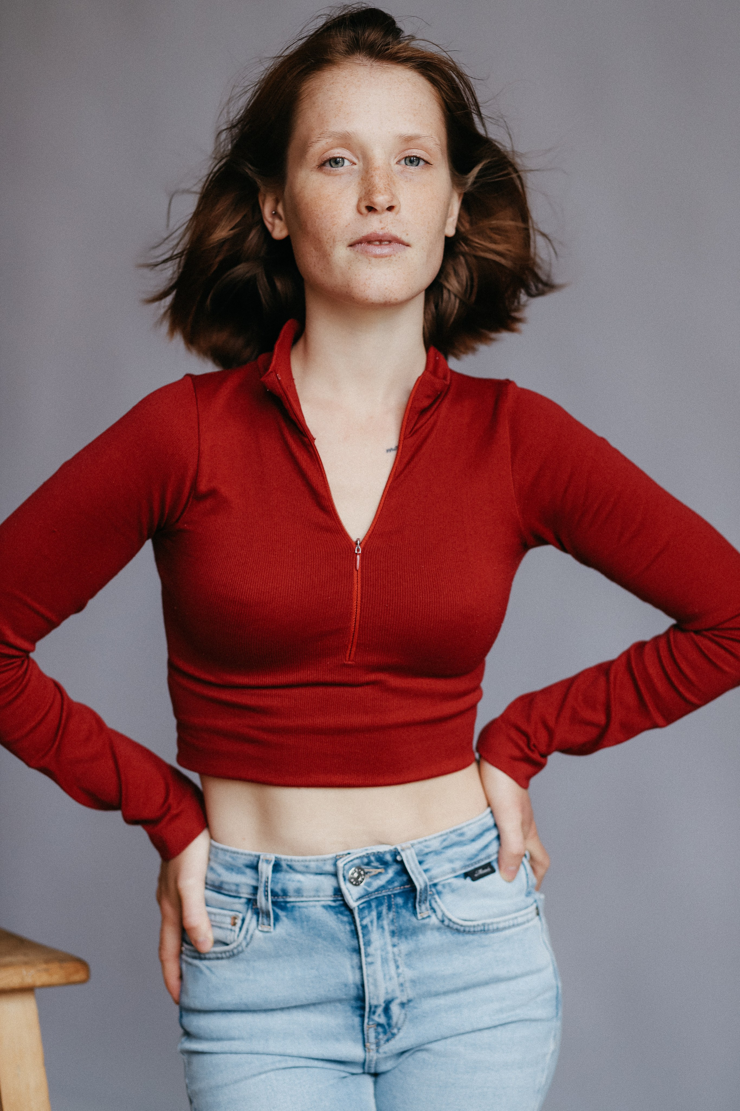 Девушка с веснушками в красном топе и голубых джинсах