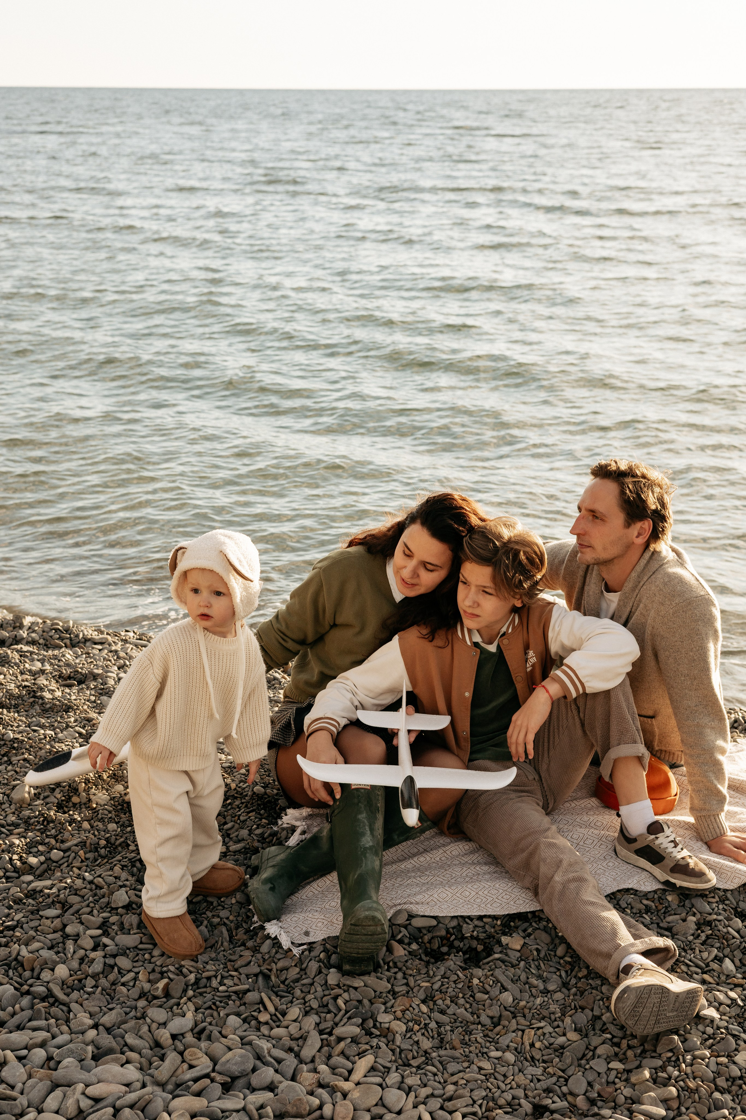 Родители нежно обнимают детей на фоне закатного моря