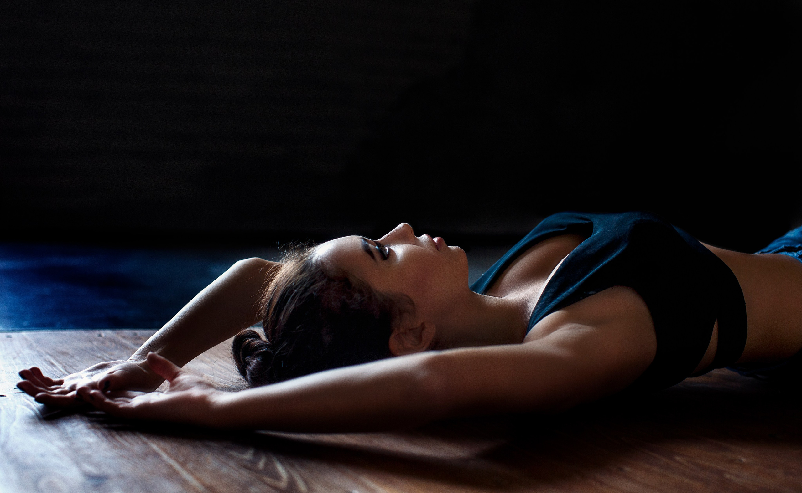 красивая модель девушка лежит на деревянном полу в контровом свете