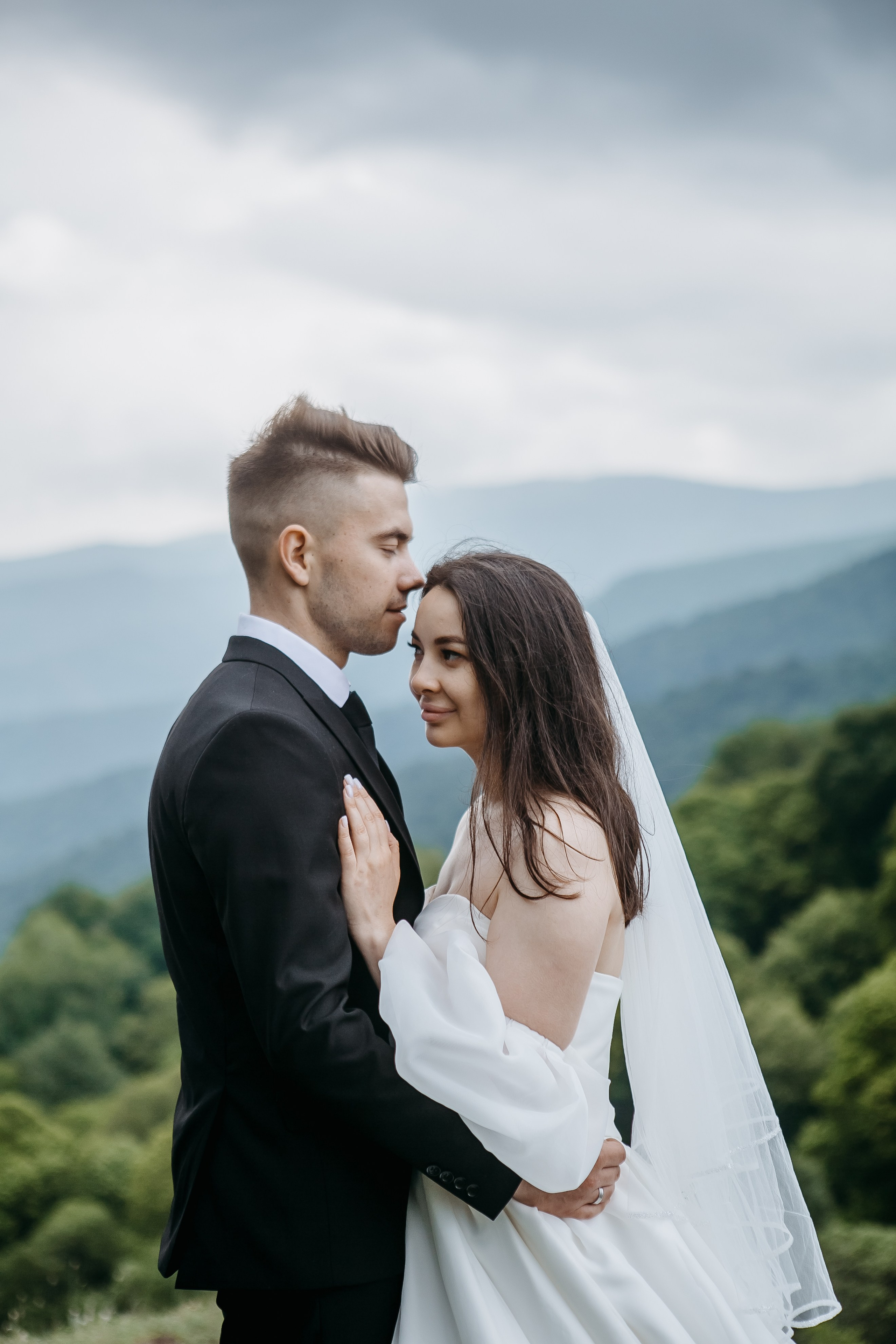Счастливая пара, танцующая на вершине горы, окруженная потрясающим природным пейзажем Кавказа