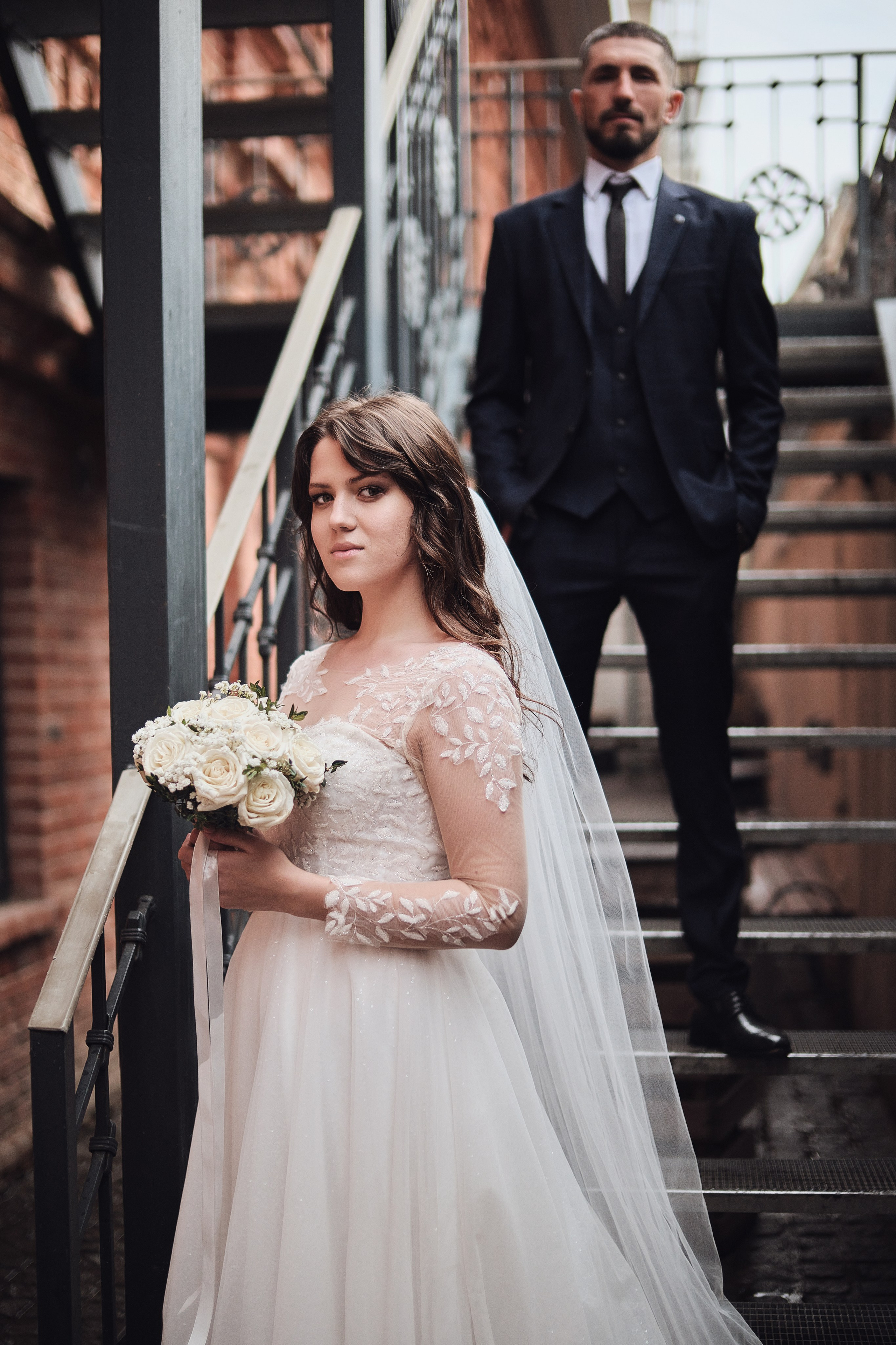 Семейный портрет: родители молодожёнов обнимают супругов перед фасадом загородного ресторана в Камышине