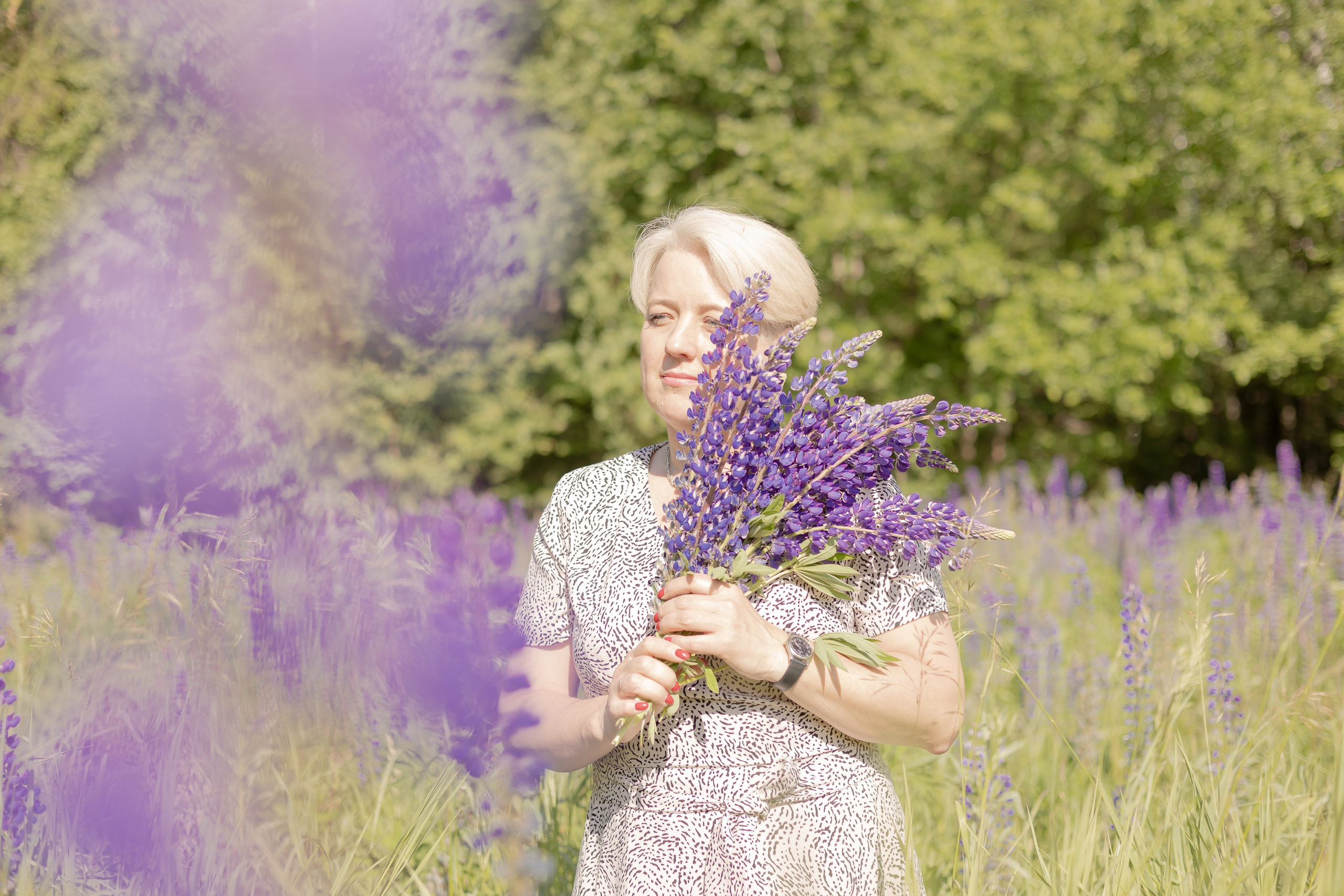 Женщина прижимает к груди букет из люпинов