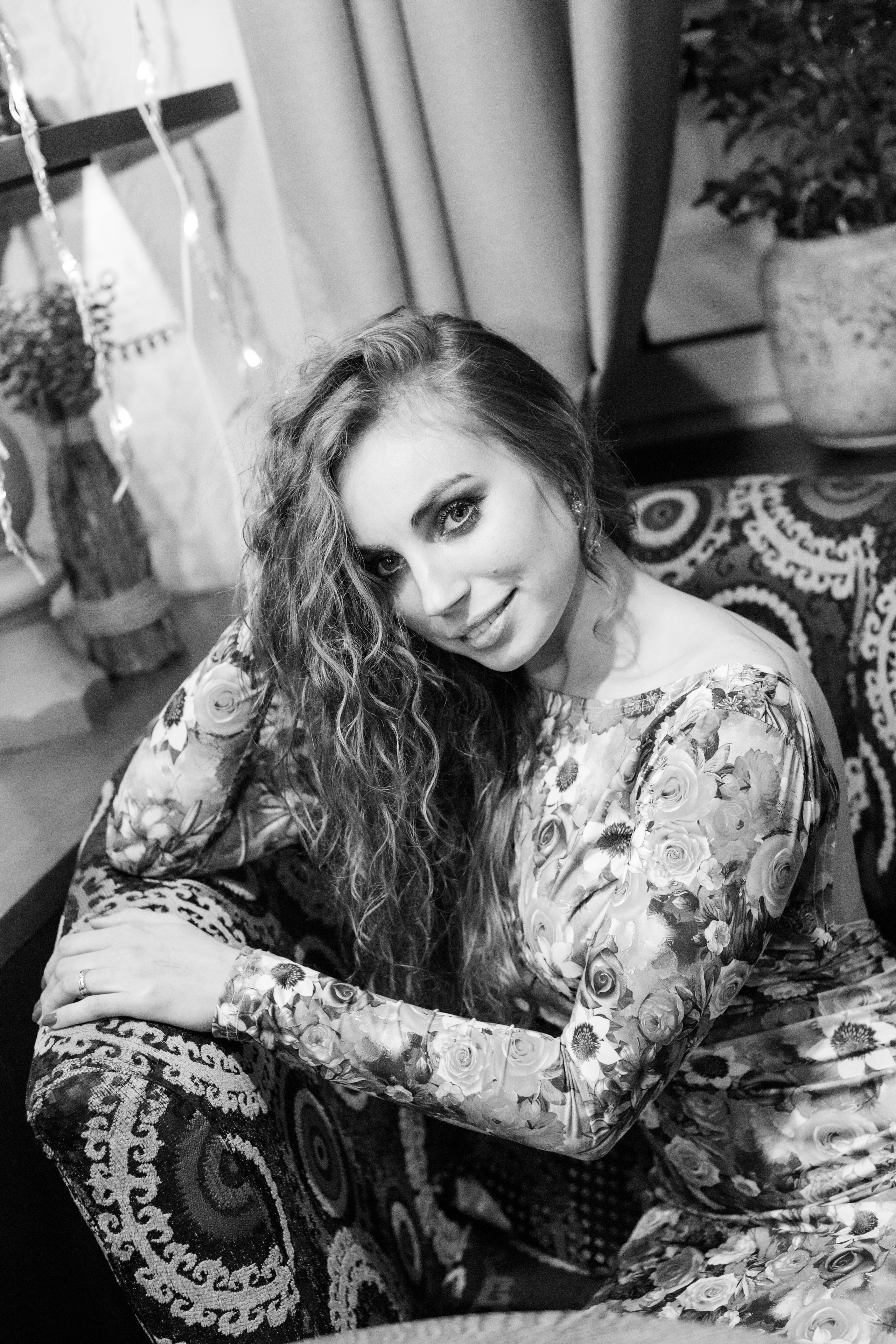 индивидуальное черно белое фото где девушка сидит на диване положив руку себе на голову 