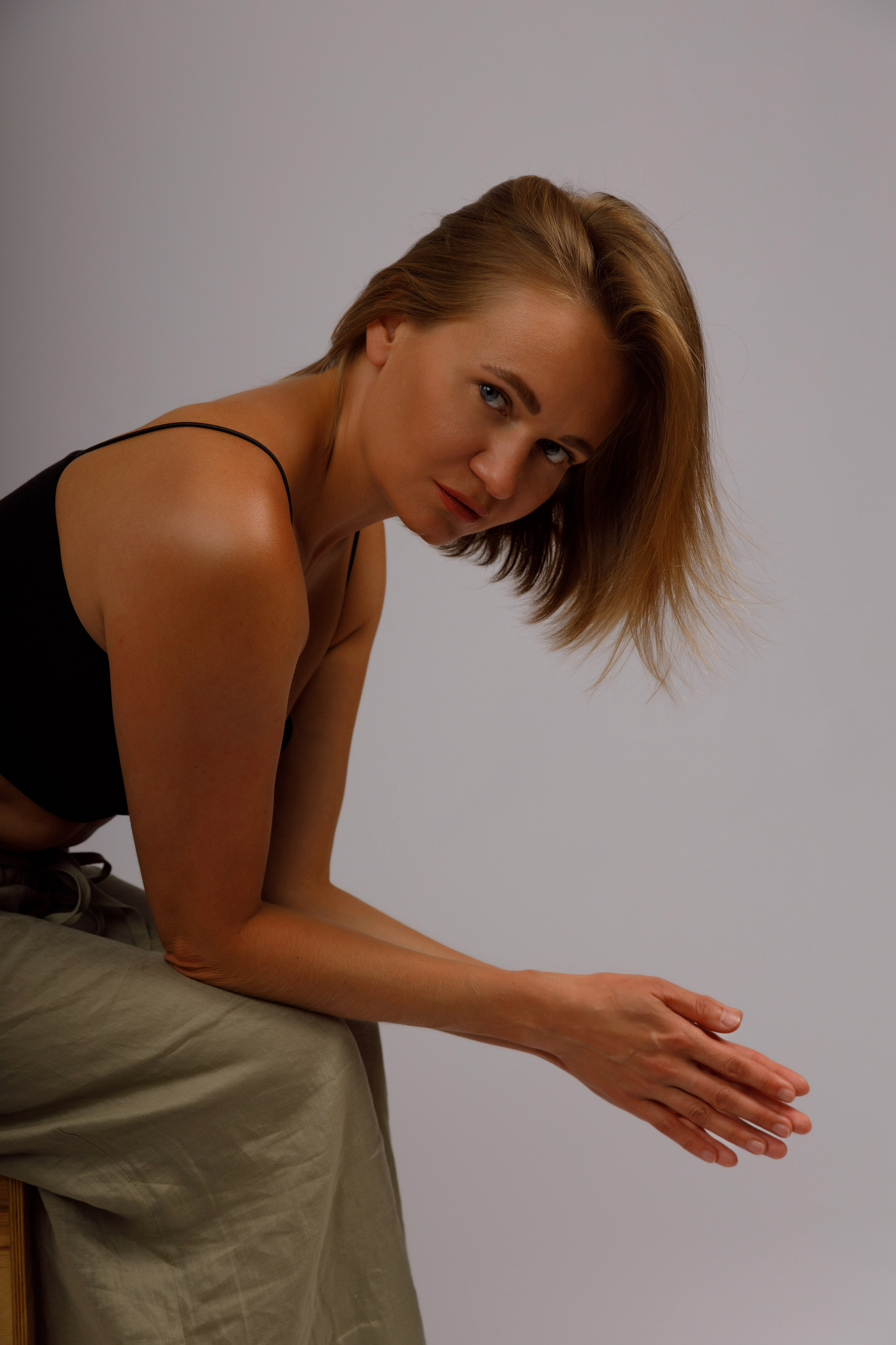 Портрет девушки сидящей на стуле с ниспадающими волосами в низком ключе.