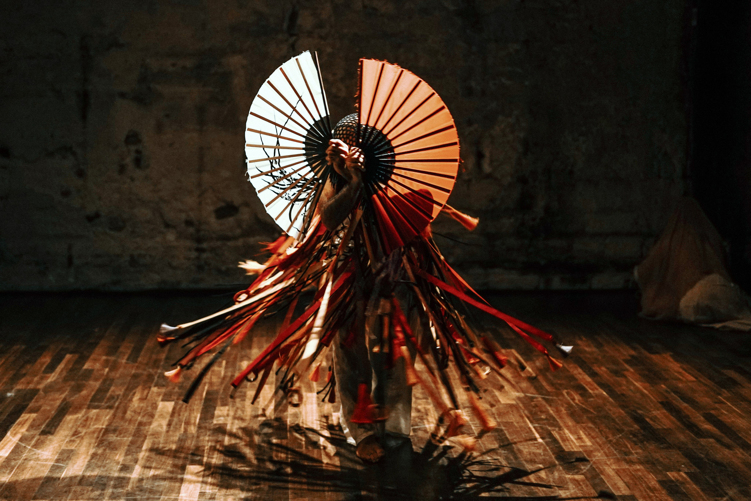 Dancer with white and red fans in fringed red costume, backlit, Festival SOUM Paris — photo by Anna Ulianova / Танцор с белым и красным веерами в красном костюме с бахромой, контровой свет, фестиваль SOUM, Париж — фото Анны Ульяновой