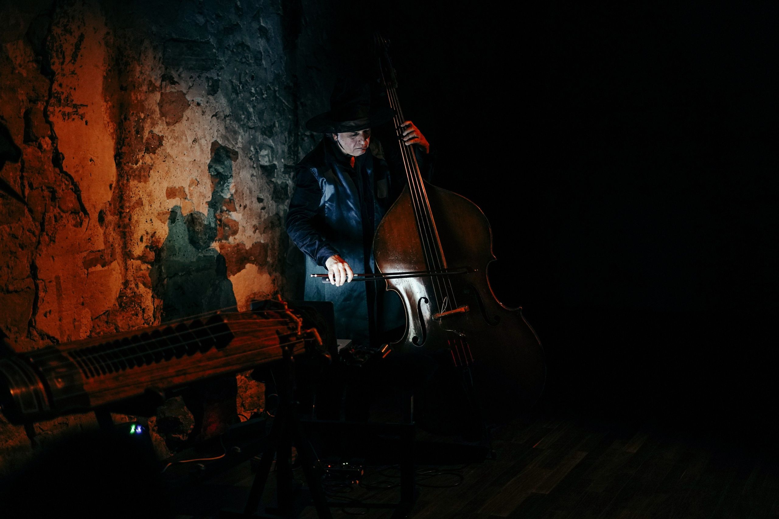 Double bass player in a hat in a dark brick space, live music for dance performance Paris — photo by Anna Ulianova / Контрабасист в шляпе в тёмном кирпичном зале, живая музыка для перфоманса, Париж — фото Анны Ульяновой