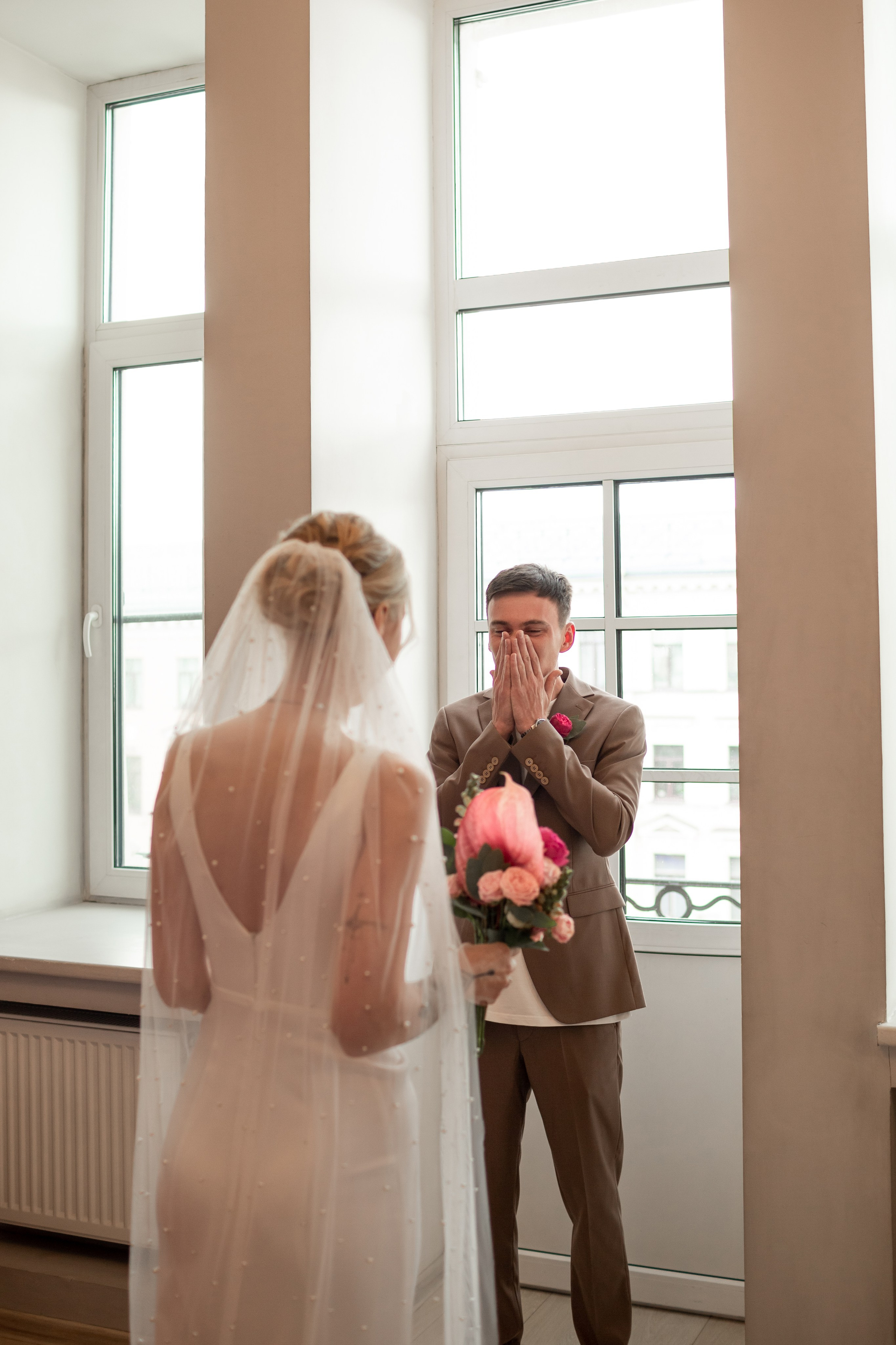 Трогательная реакция жениха на первой встрече с невестой в красивом платье и с фатой, жених плачет.