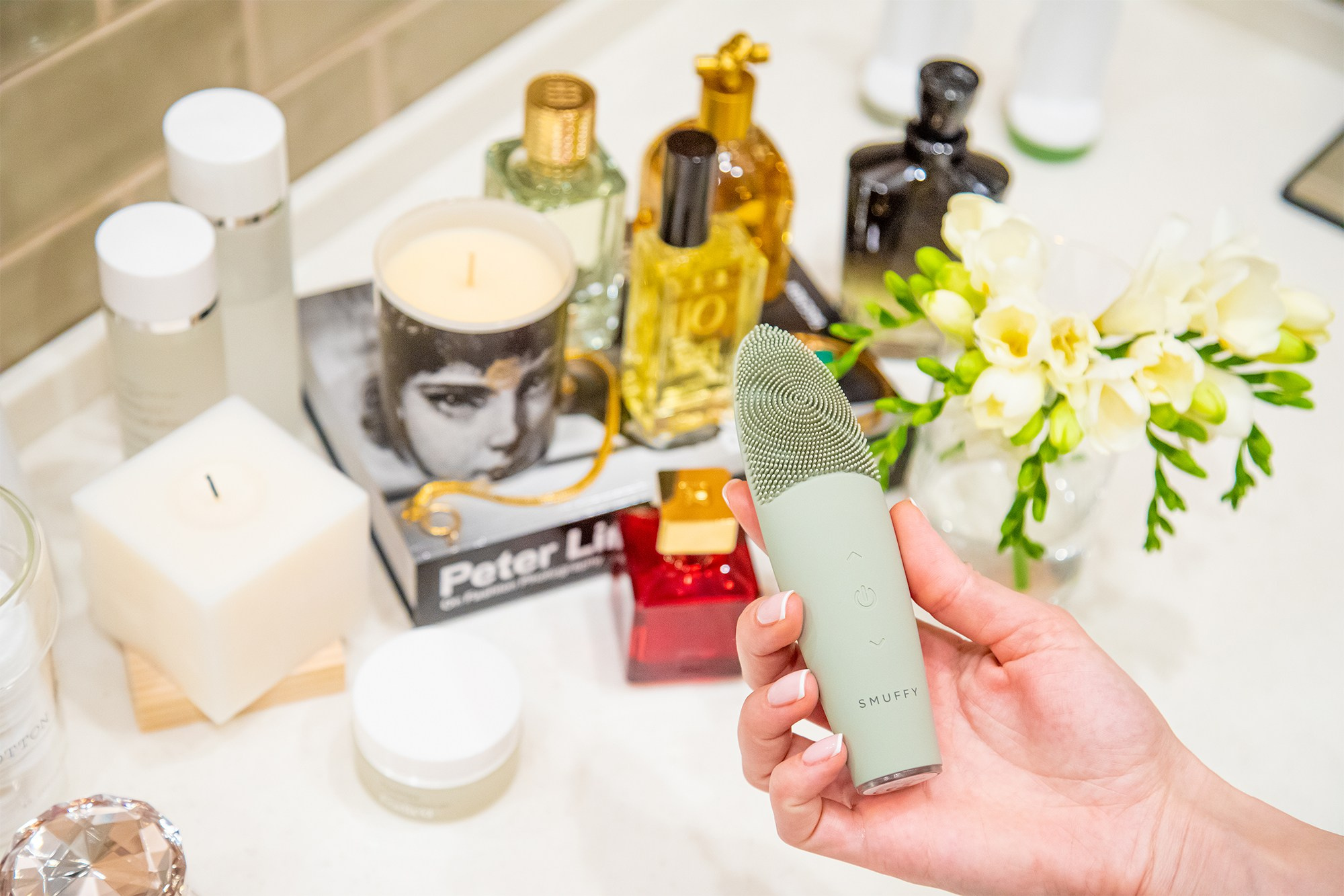 Массажер для лица смуффи в интерьере серо-зеленый в руке