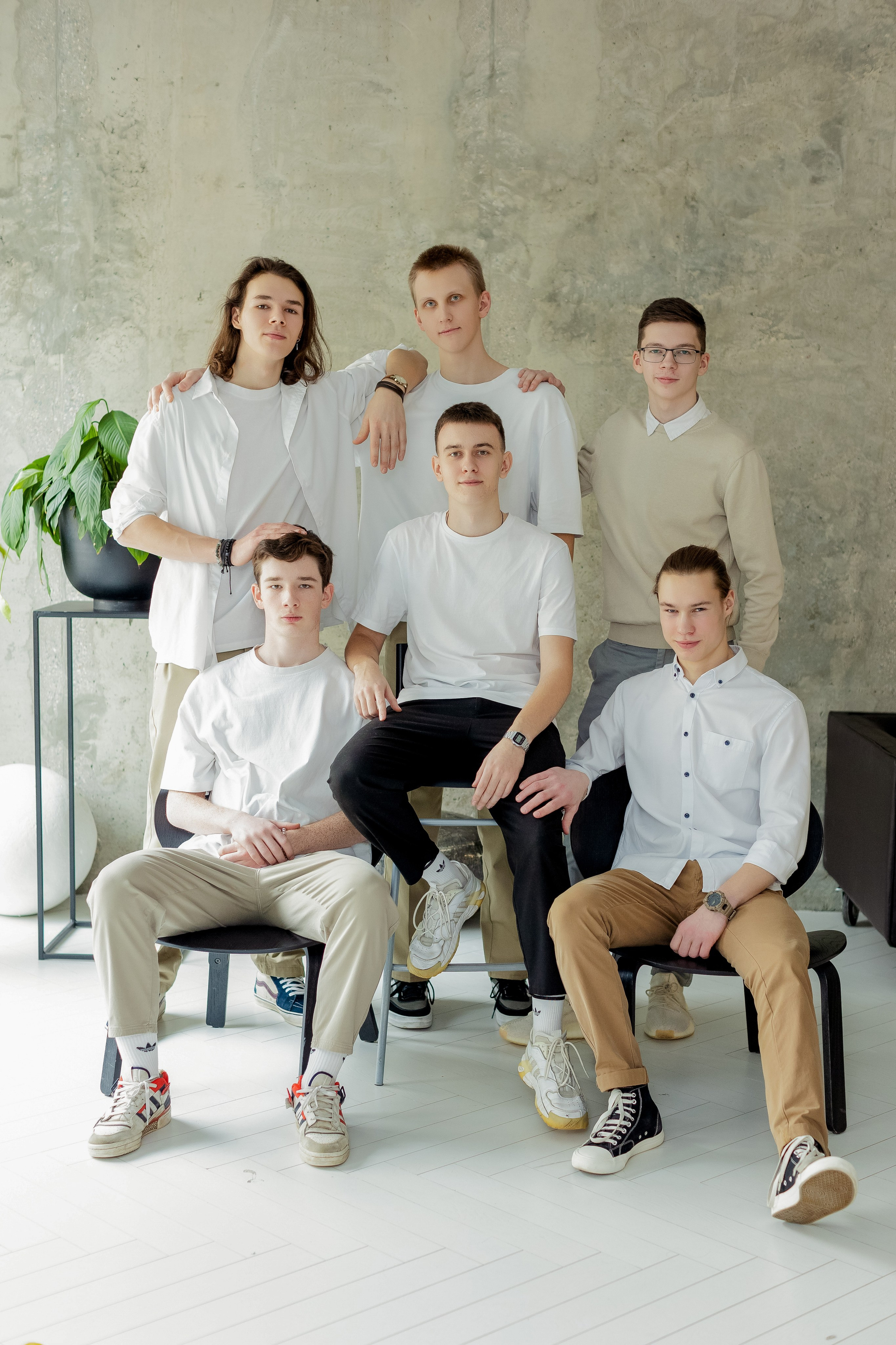Группа молодых людей сидят на стульях в фотостудии