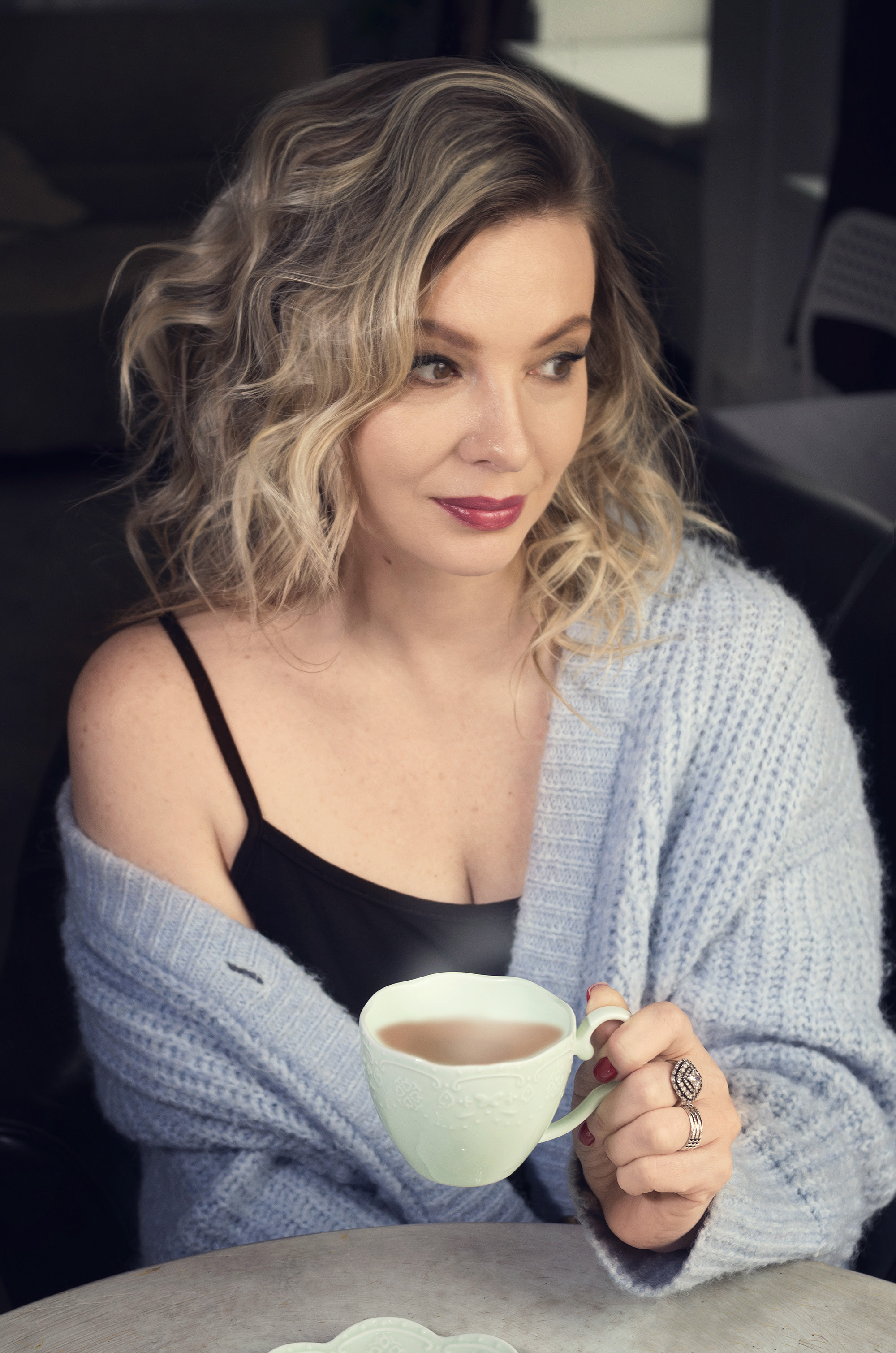 Портрет блондинки в голубой кофте. В руках чашка кофе.