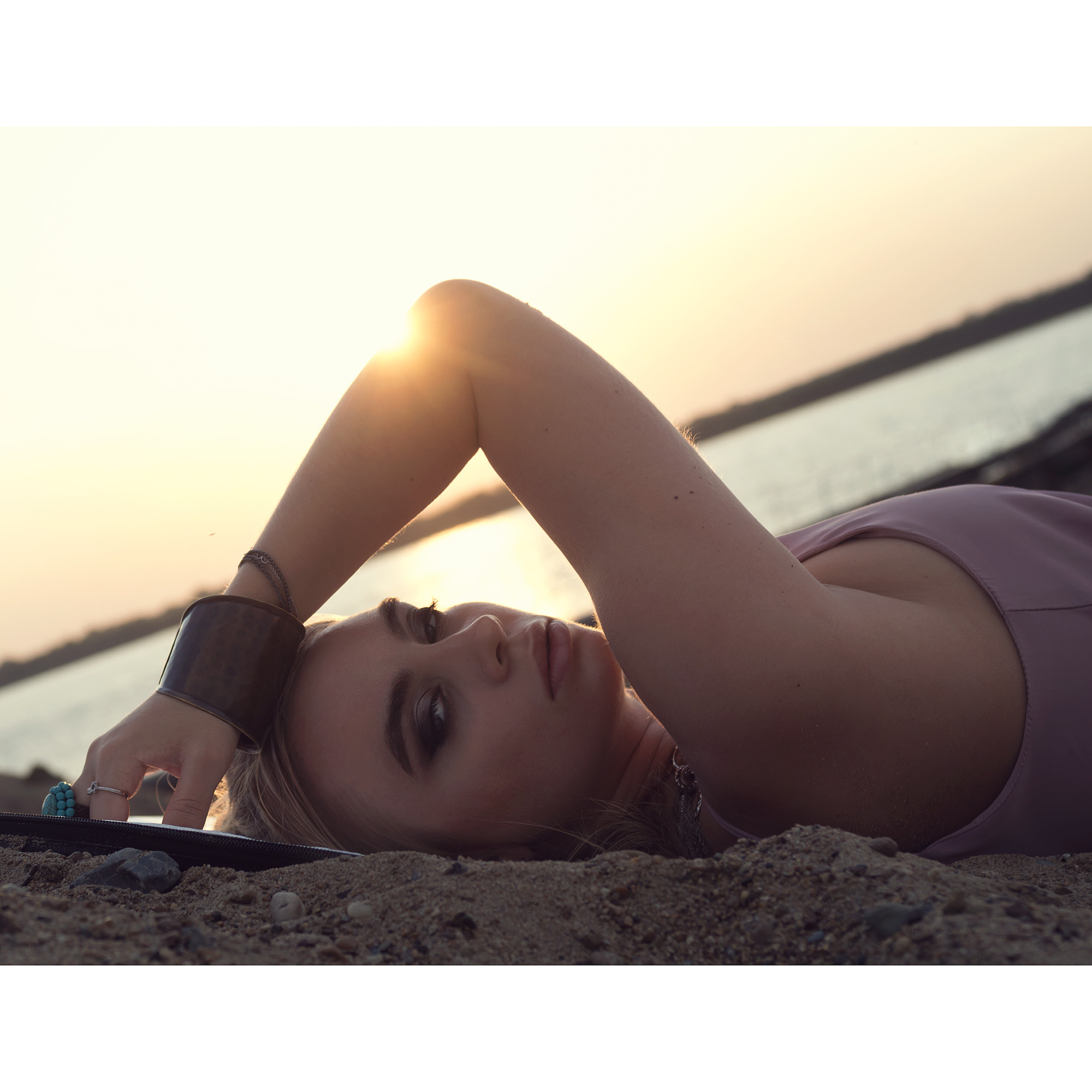 Девушка лежит на песке, крупный портрет. Летняя фотосессия на природе. Закатное освещение