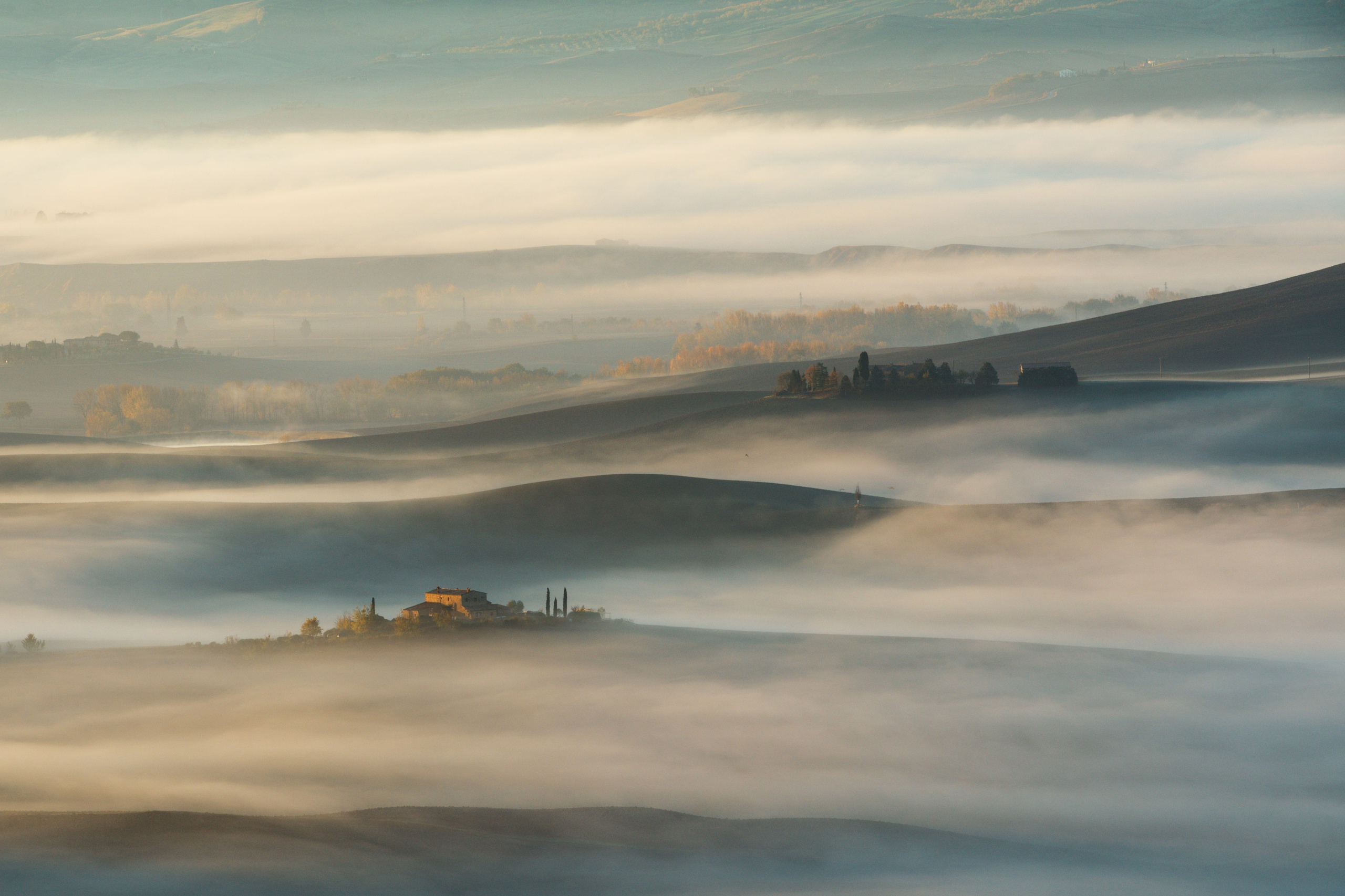  Тосканский дом, освещенный теплыми огнями, возвышается над морем плотного тумана на рассвете, подчеркивая изоляцию и мистическую атмосферу.