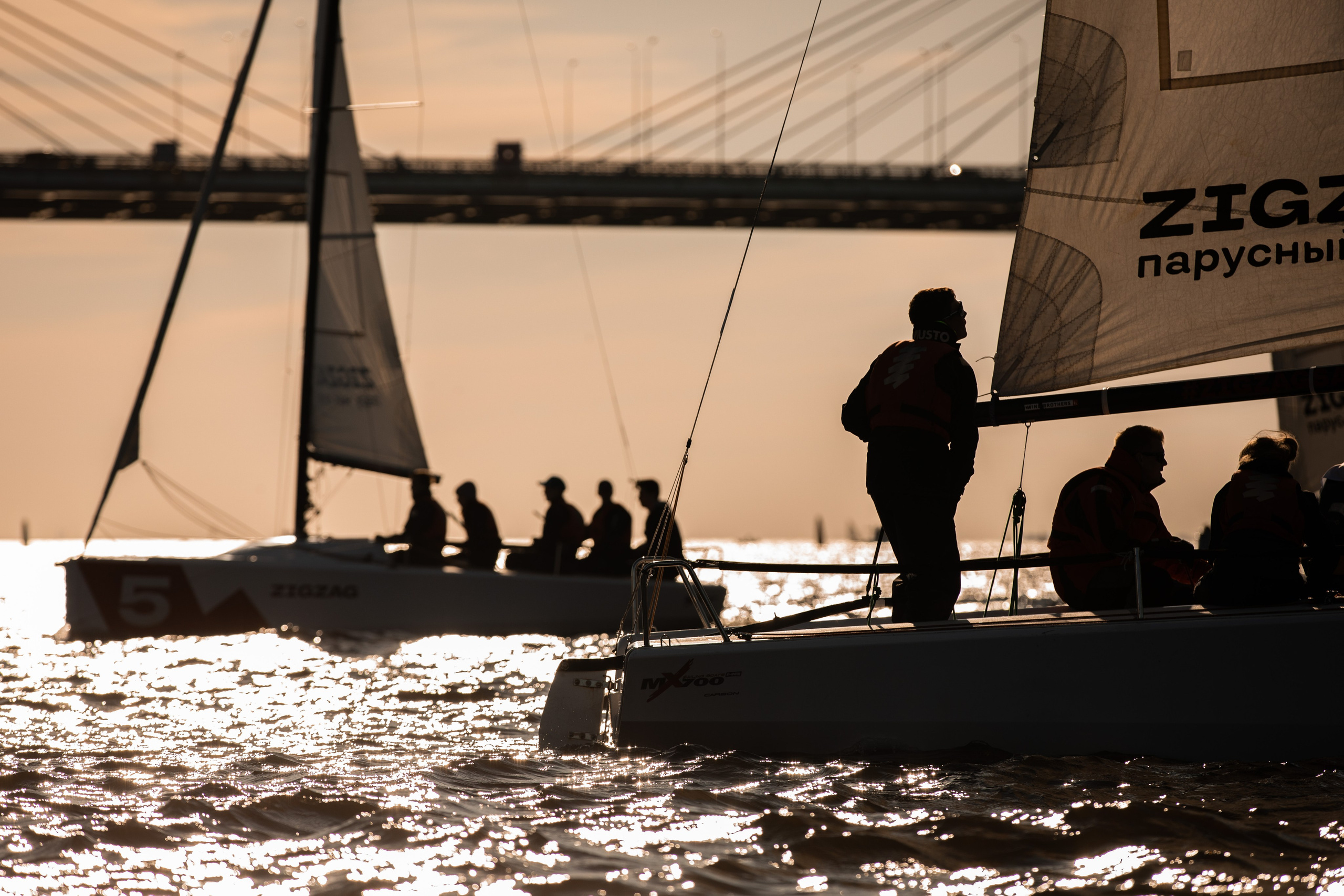 Яхты и мост в контровом свете на регате на закате в Спб.