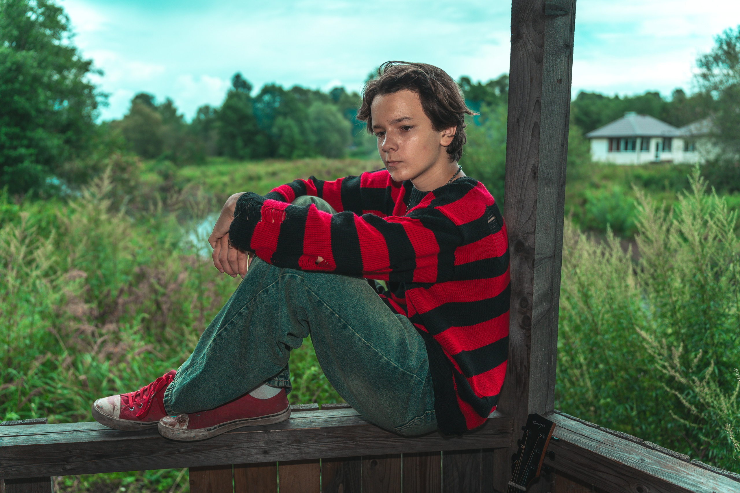 Молодой человек сидит на перилах на природе