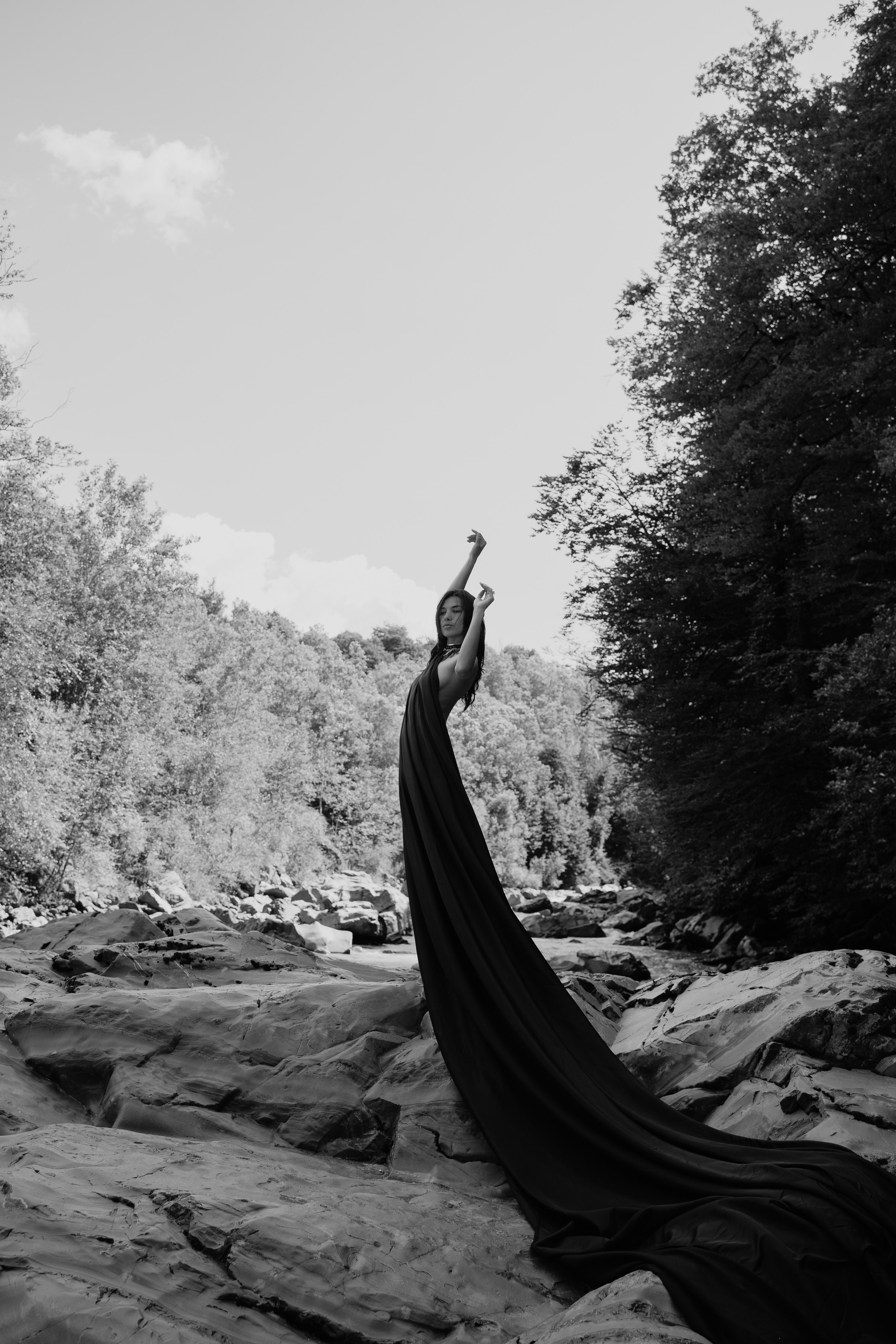 Черно белый снимок девушки с тканью на камнях