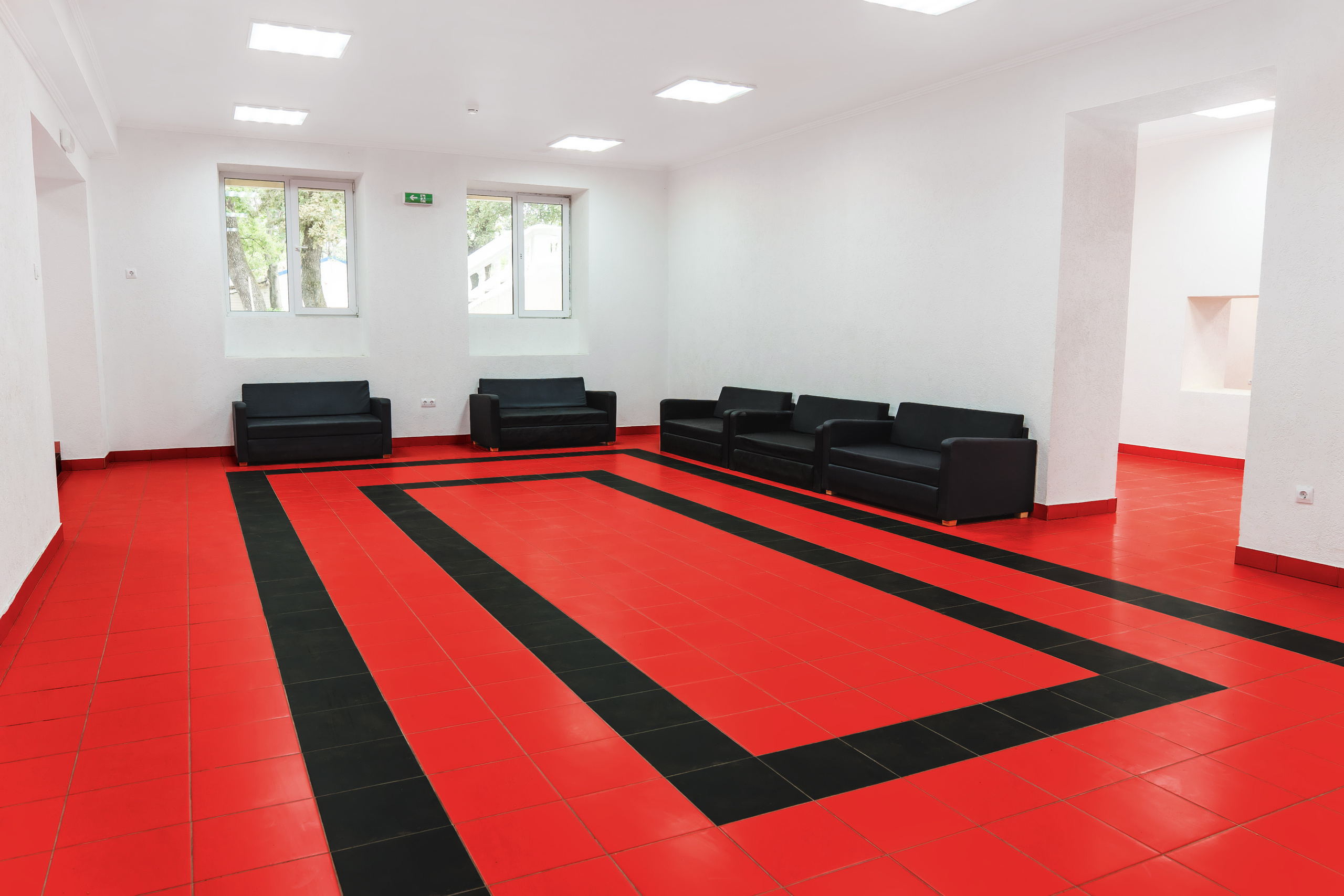 Помещение для занятий и мастер-классов с черной мебелью, диванами и креслами, красный пол с черным узором