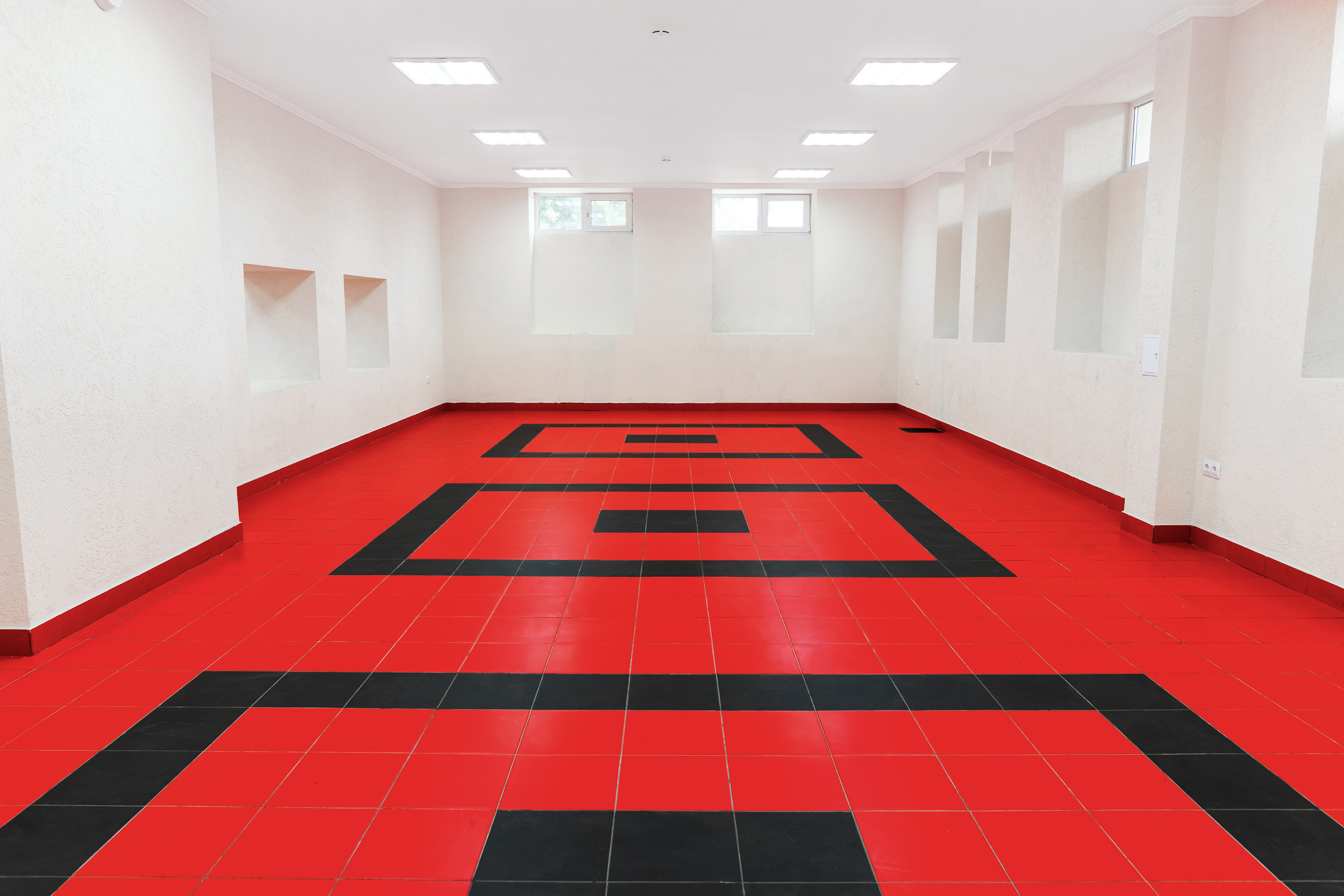 Помещение для занятий, уроков, мастер-классов, со светлыми стенами и красным полом с черным узором.