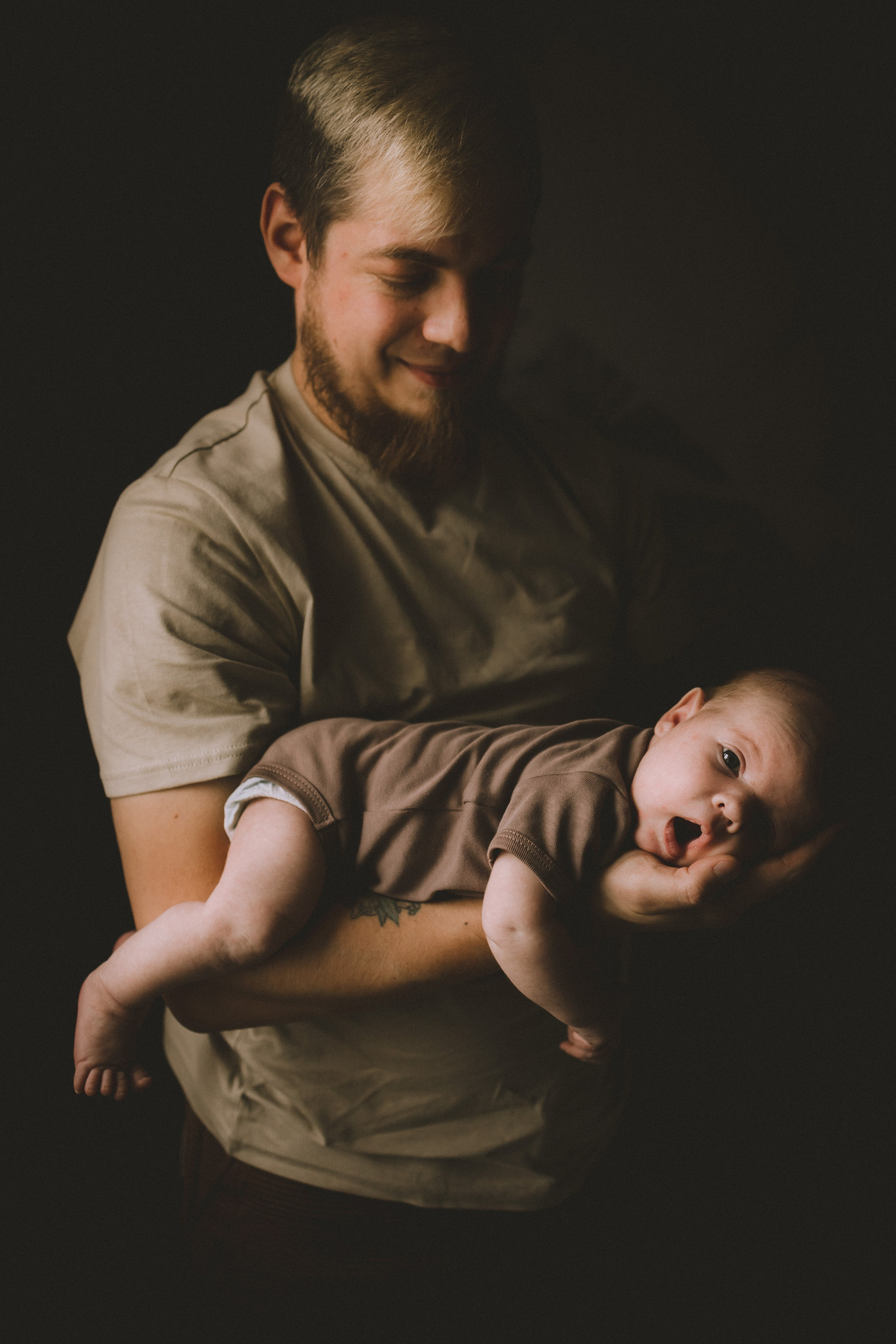 Сильный папа и крохотный малыш у него на руке фотосессия новорождённого дома