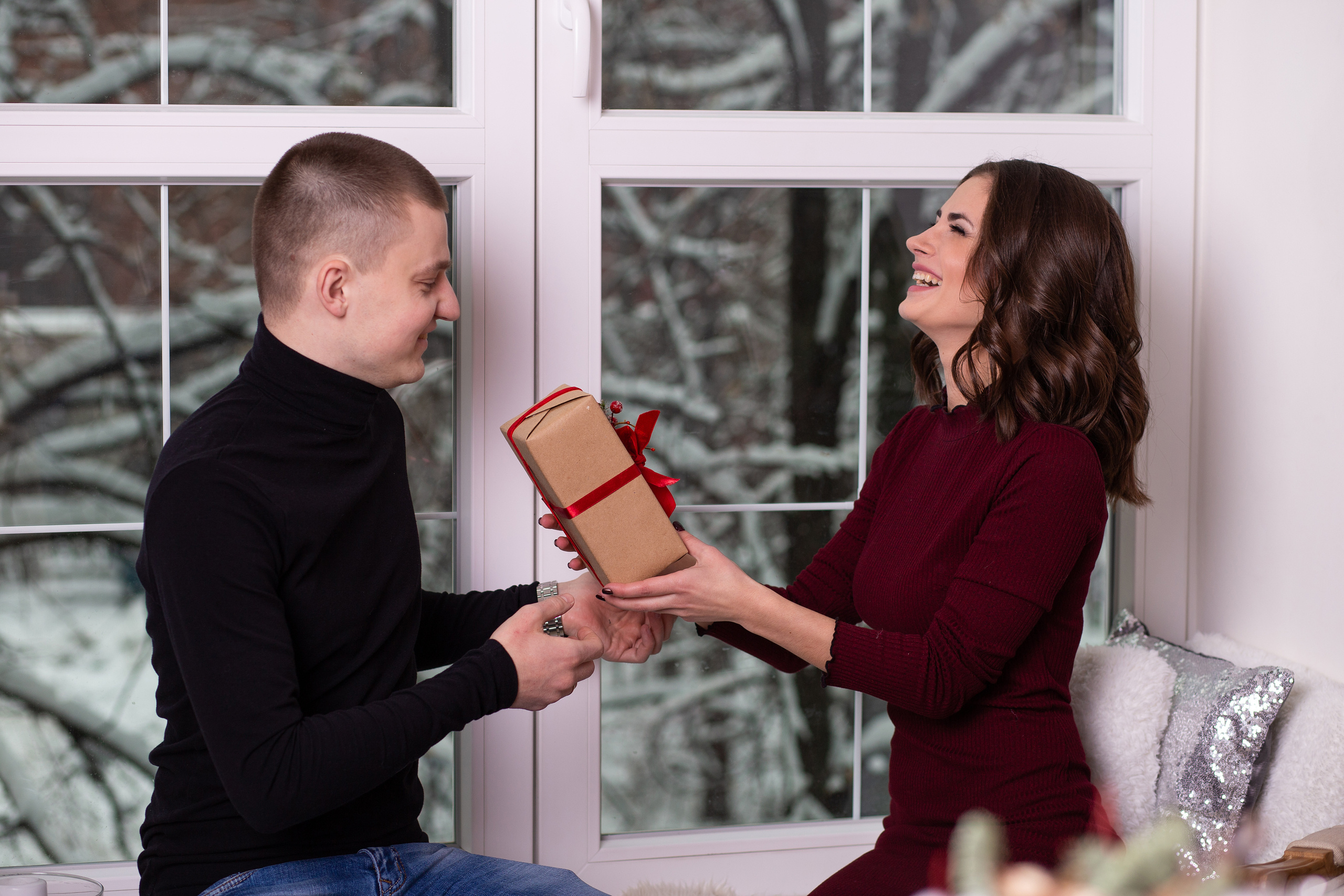 Девушка  и  молодой  человек сидят на  подоконнике. Они  обмениваются подарками.