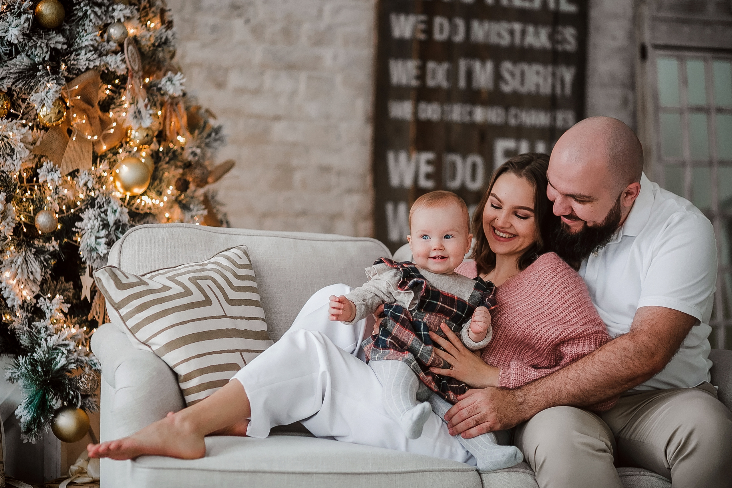 Новогодняя семейная фотосессия в студии на диване мама папа с малышом