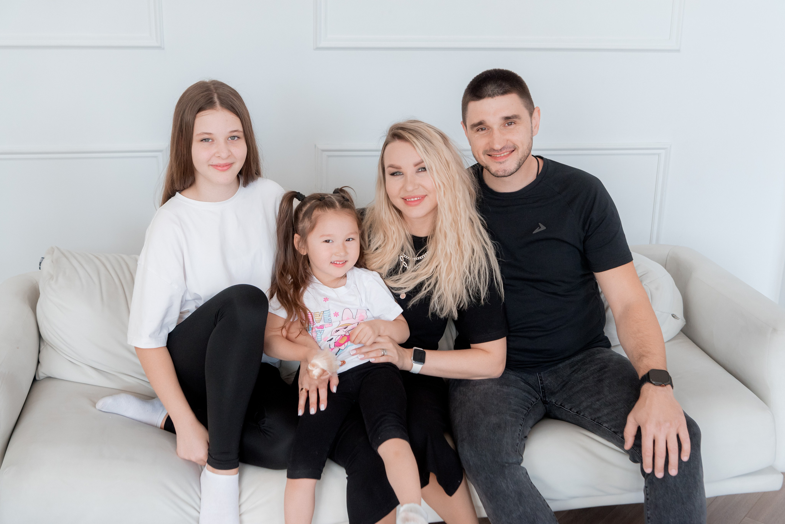 Студийный семейный портрет в белых тонах - родители обнимают детей.