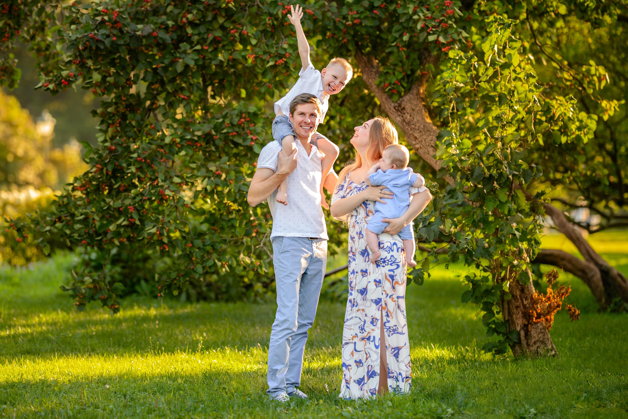 Семья с двумя детьми гуляют в парке и играют в самолеты.