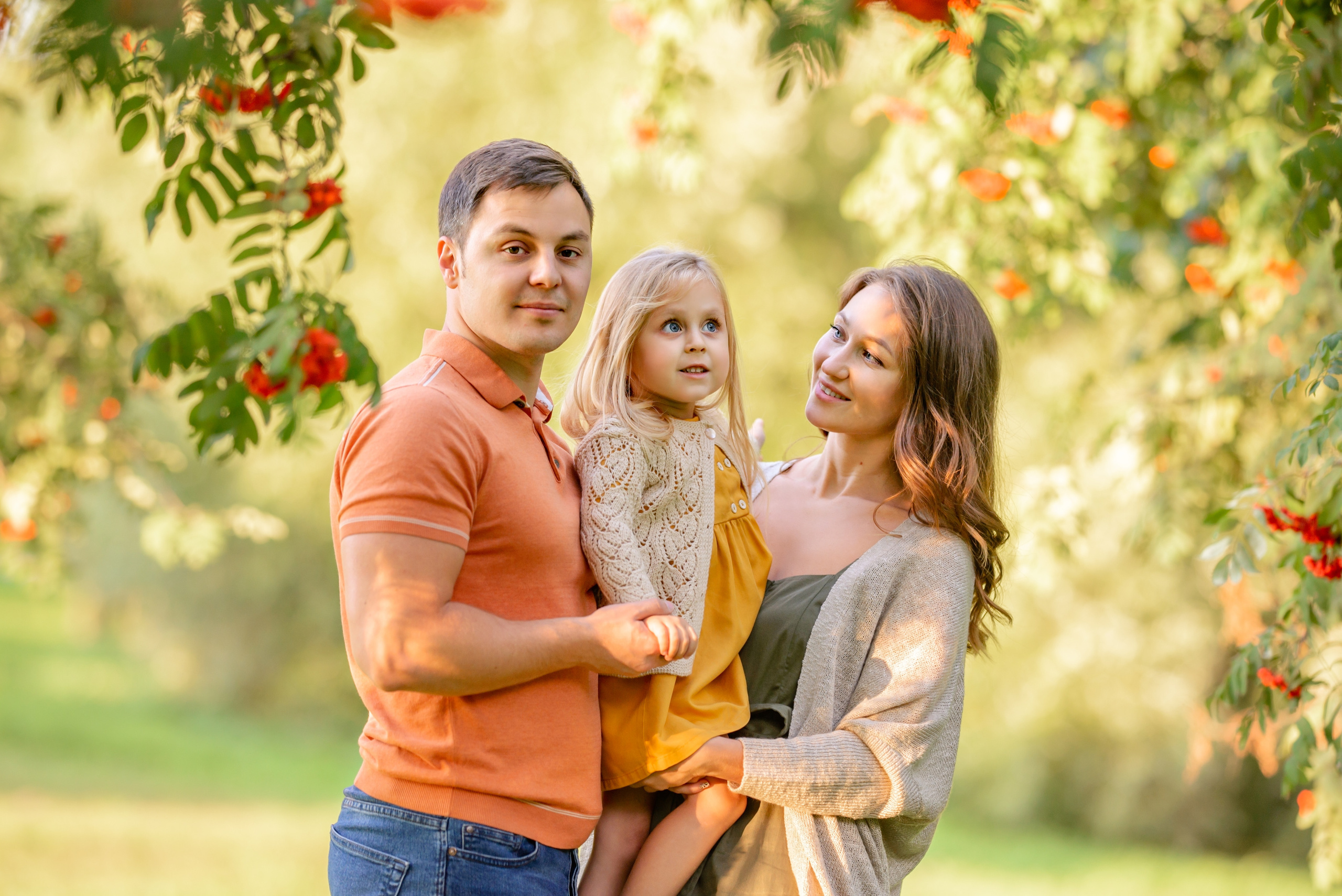 Красивая семья на фоне деревьев рябины в парке.