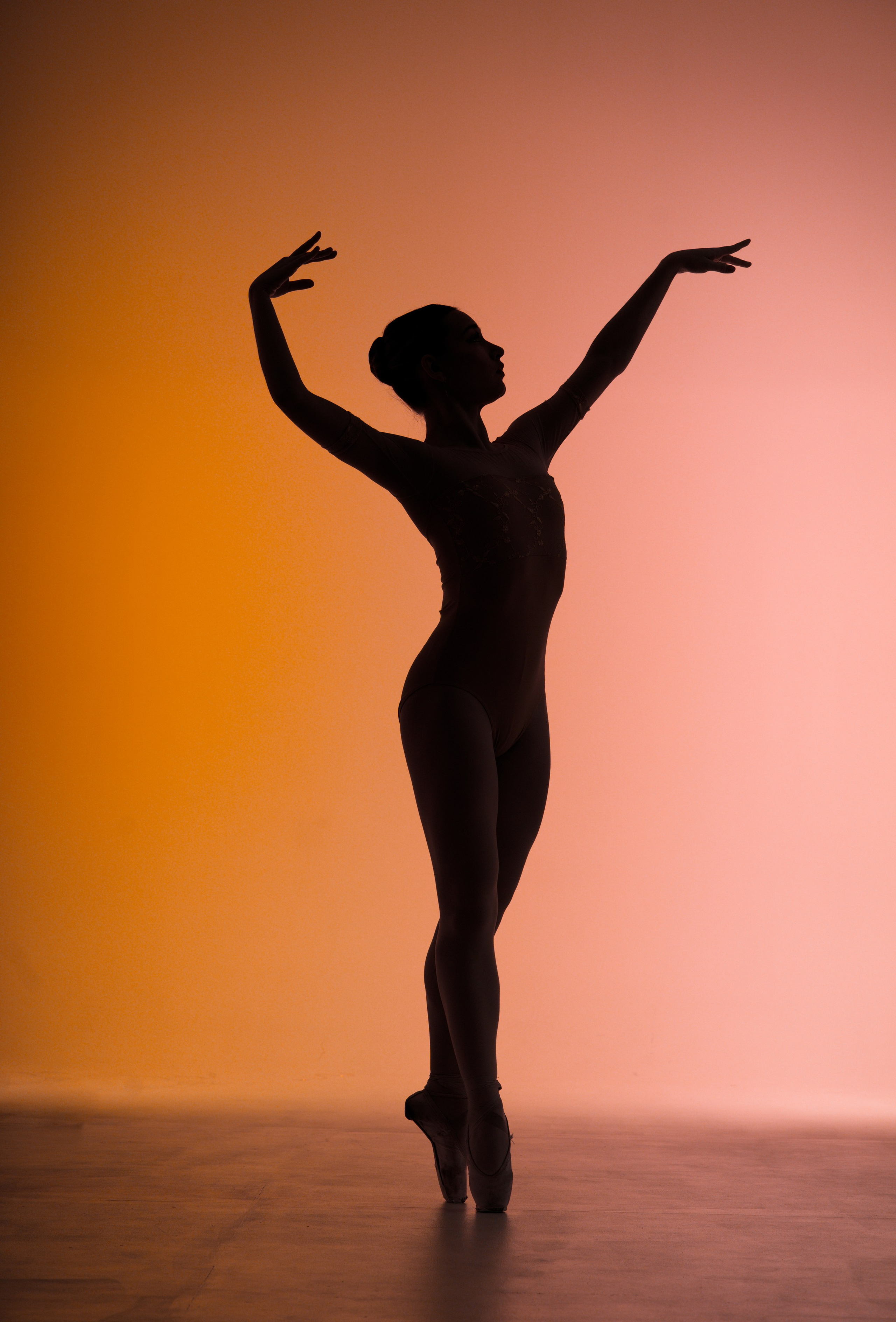 Силуэт балерины в профиль на фоне оранжевого контрового света для профессионального портфолио балерины