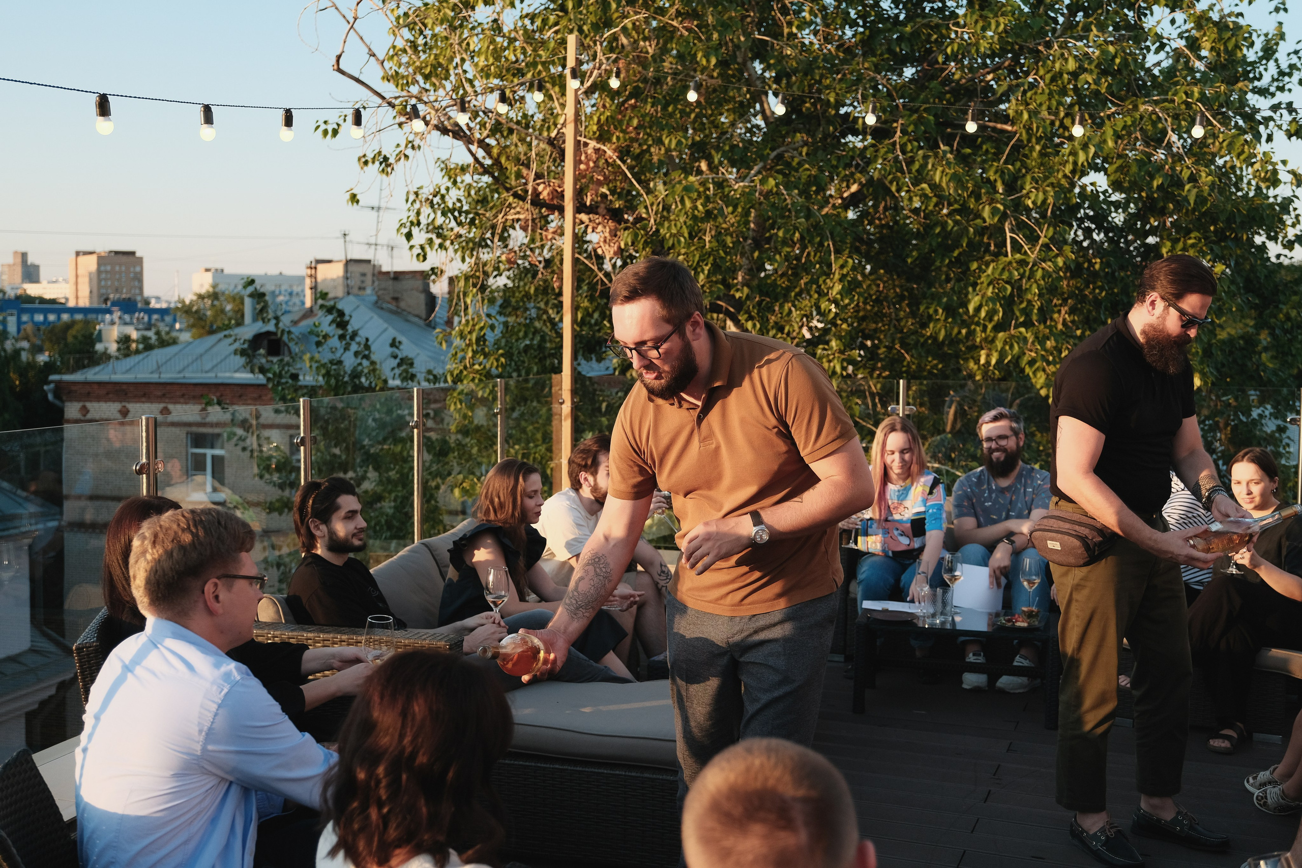 Сомелье на корпоративе разливает вино гостям.