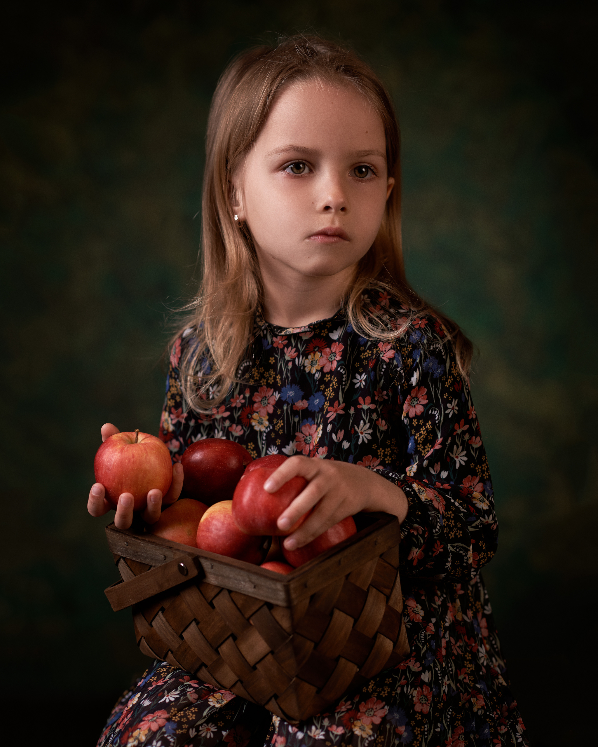 Студийный портрет ребенка с корзиной красных яблок 