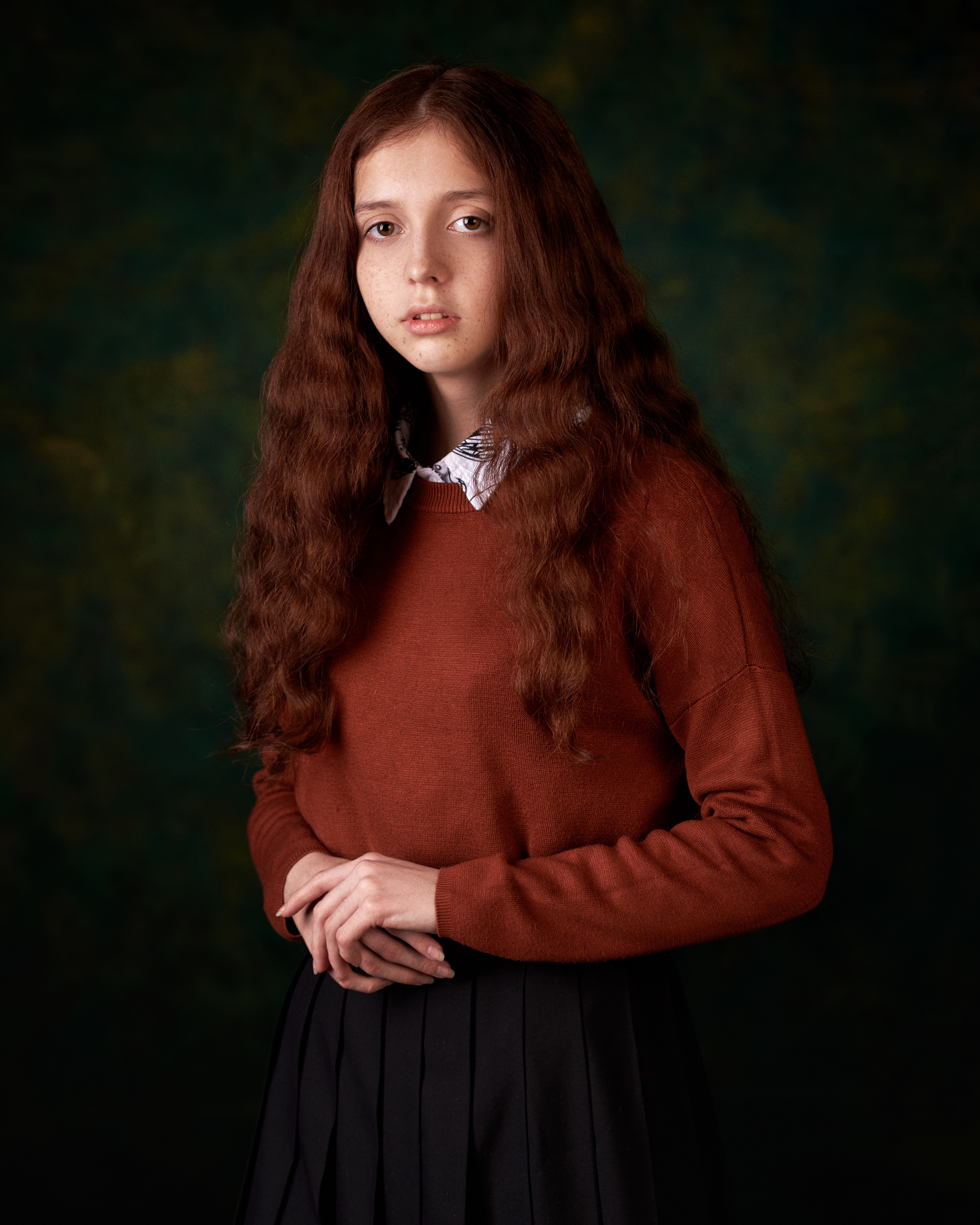 Рыжая кудрявая девочка в коричневом джемпере  