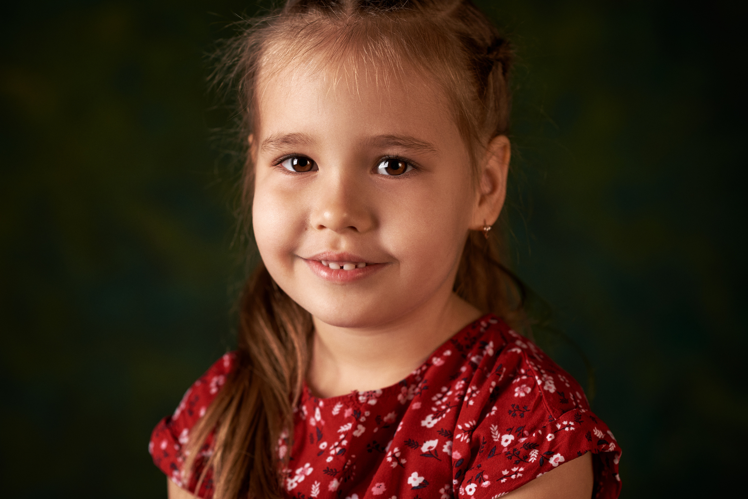 Фотография очаровательной маленькой девочки в красном платье на зеленом фоне 