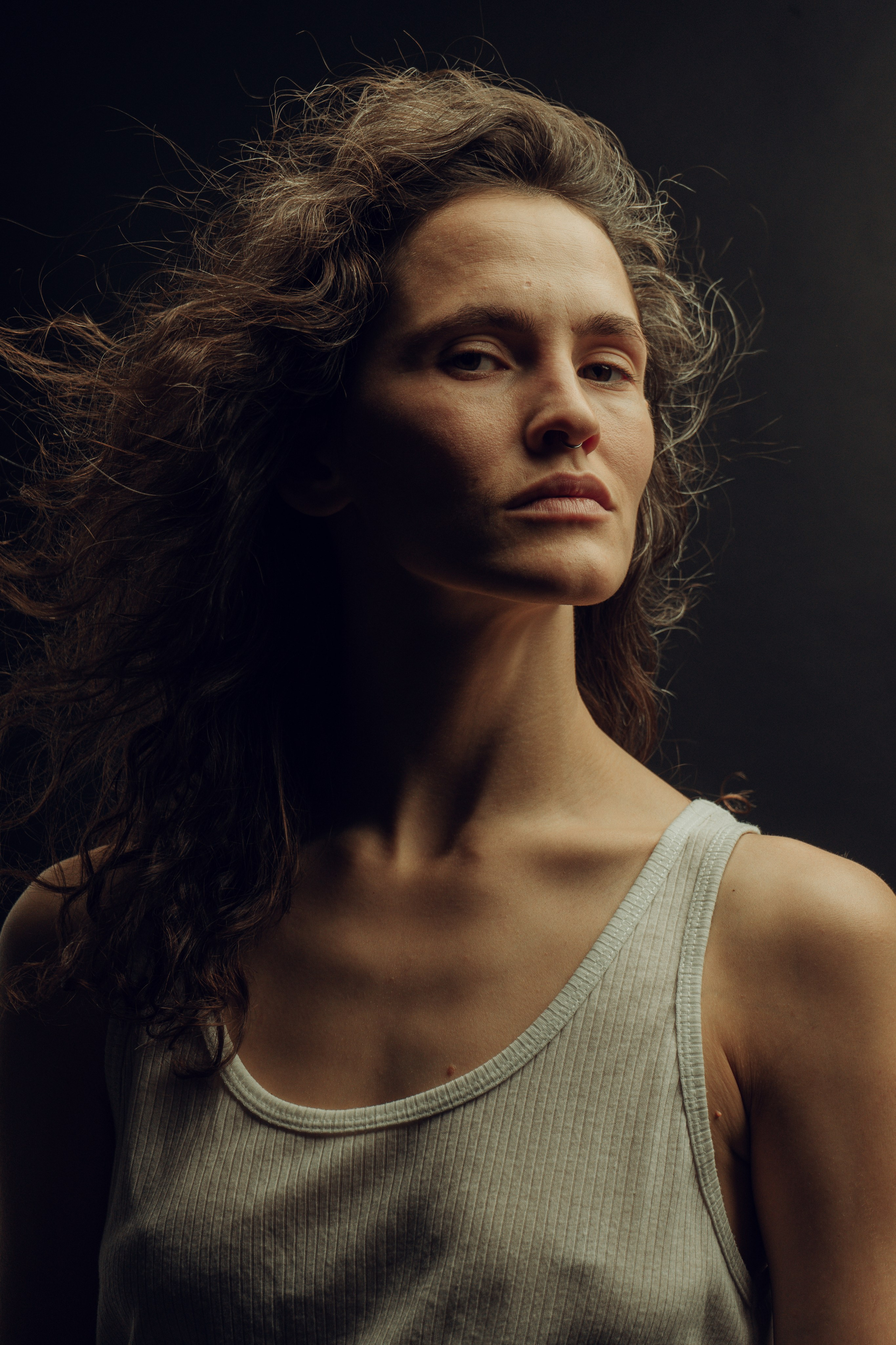 Модель в белой смотрит на фотографа и её волосы развеваются  