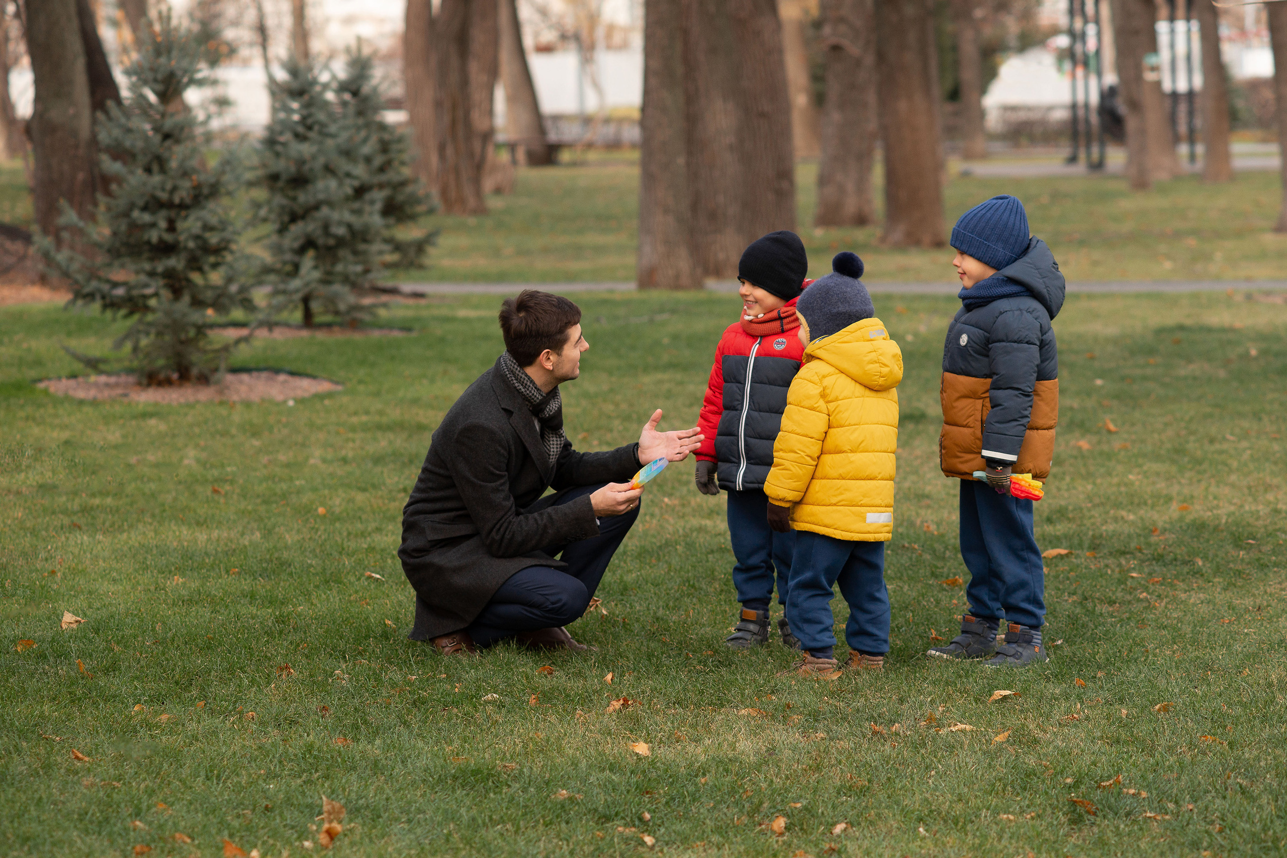 Отец в осеннем парке разговаривает с сыновьями недалеко от театральной площади Саратова.