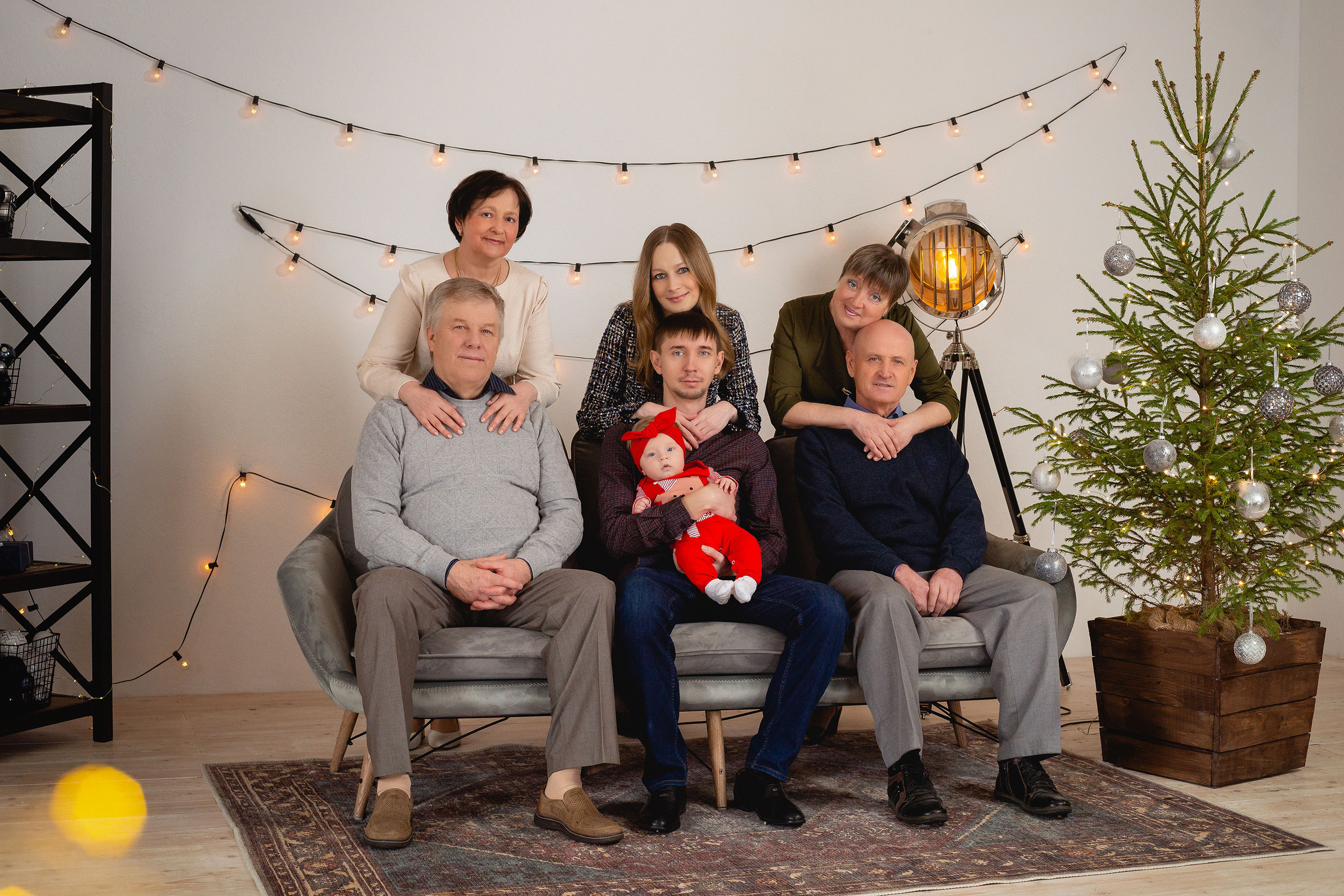 Семья из нескольких поколений на фоне новогодних декораций в фотостудии Амальгама в Саратове.